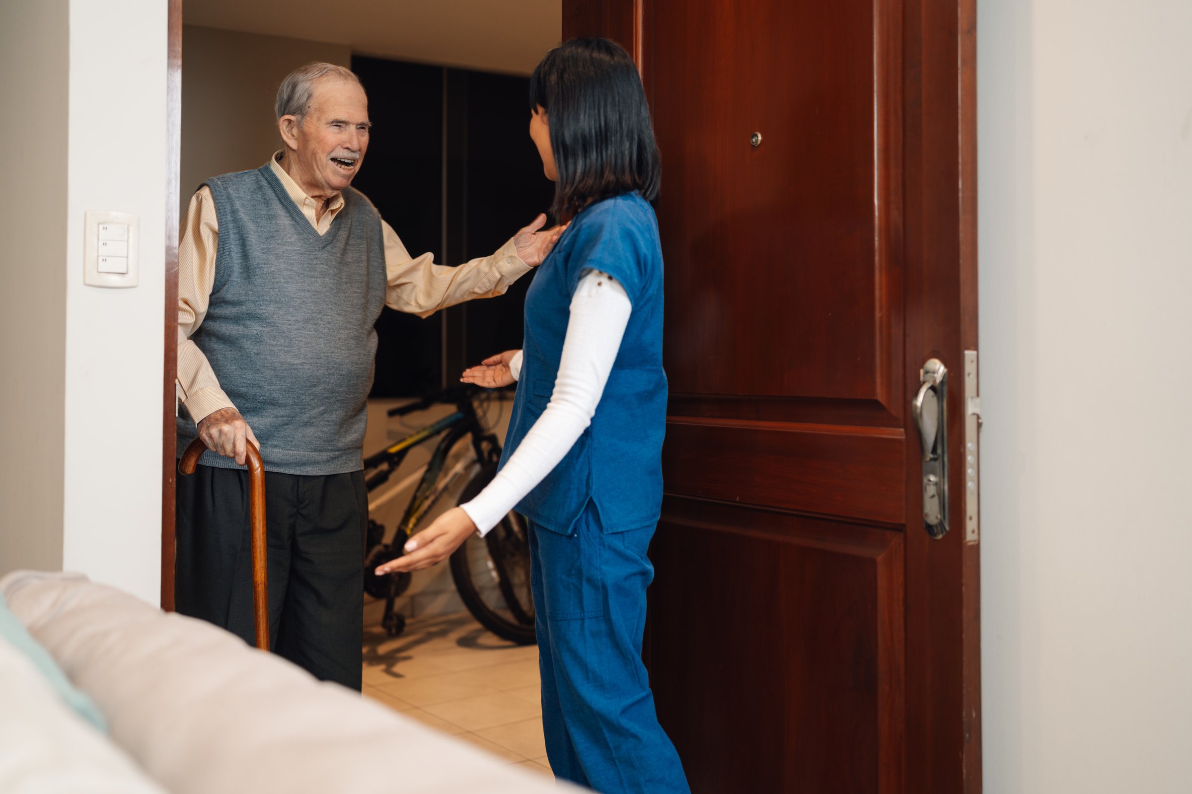 Old man with poor mobility greeting a nurse arriving for a home visit