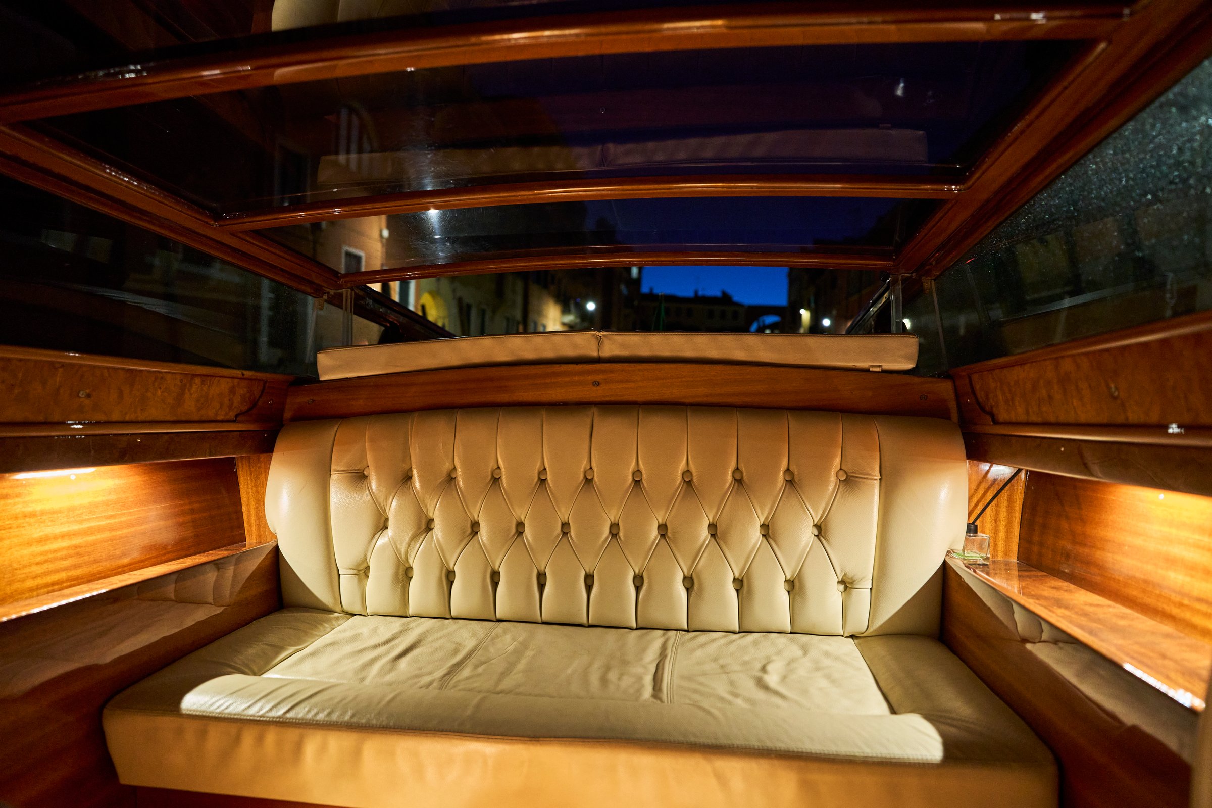Luxurious leather seating inside a wooden boat at night, showcasing elegant design and ambient lighting.