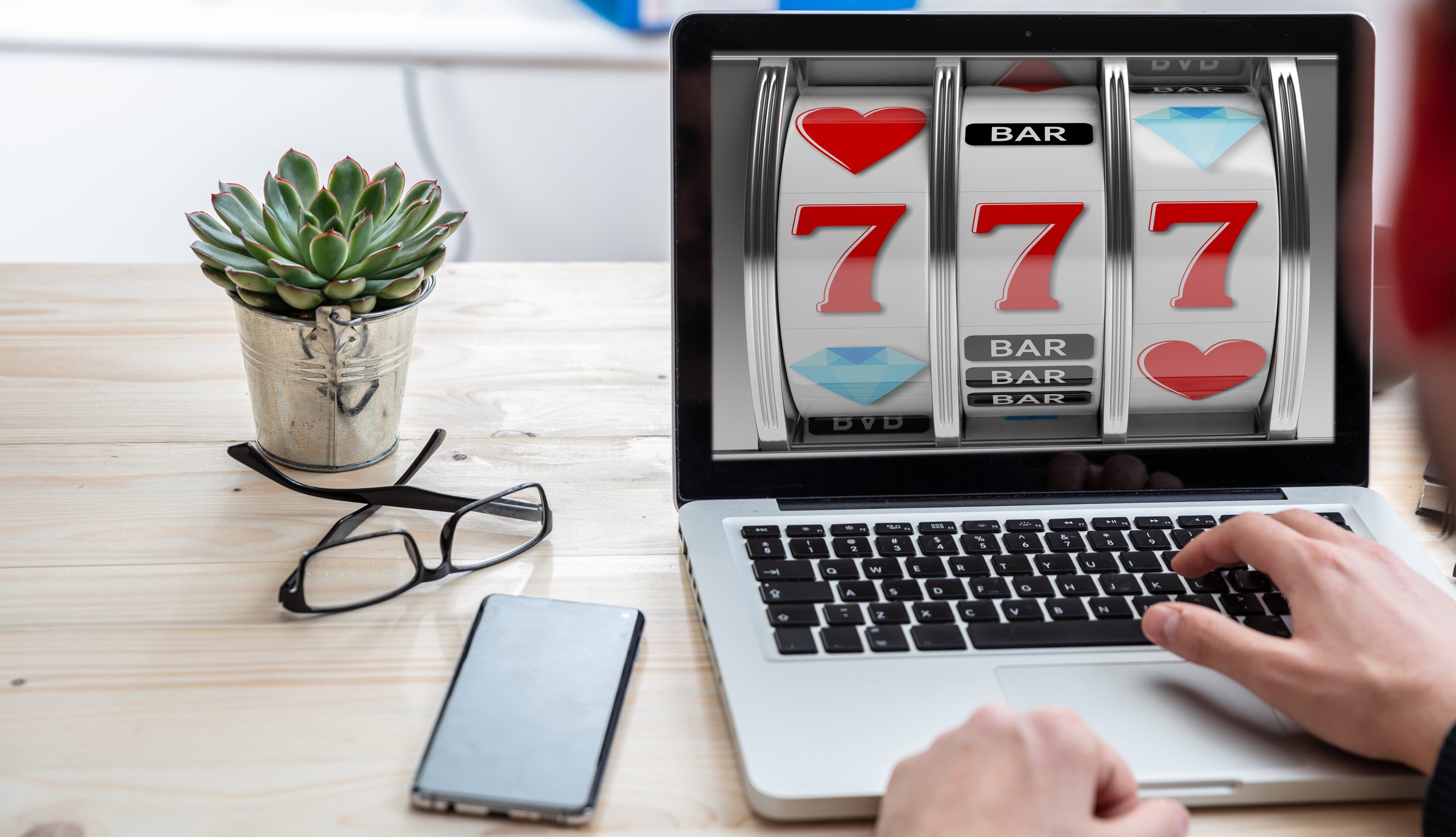 Slot machine, online casino gambling concept. Man working with a computer laptop, 777 on the screen, office business background.