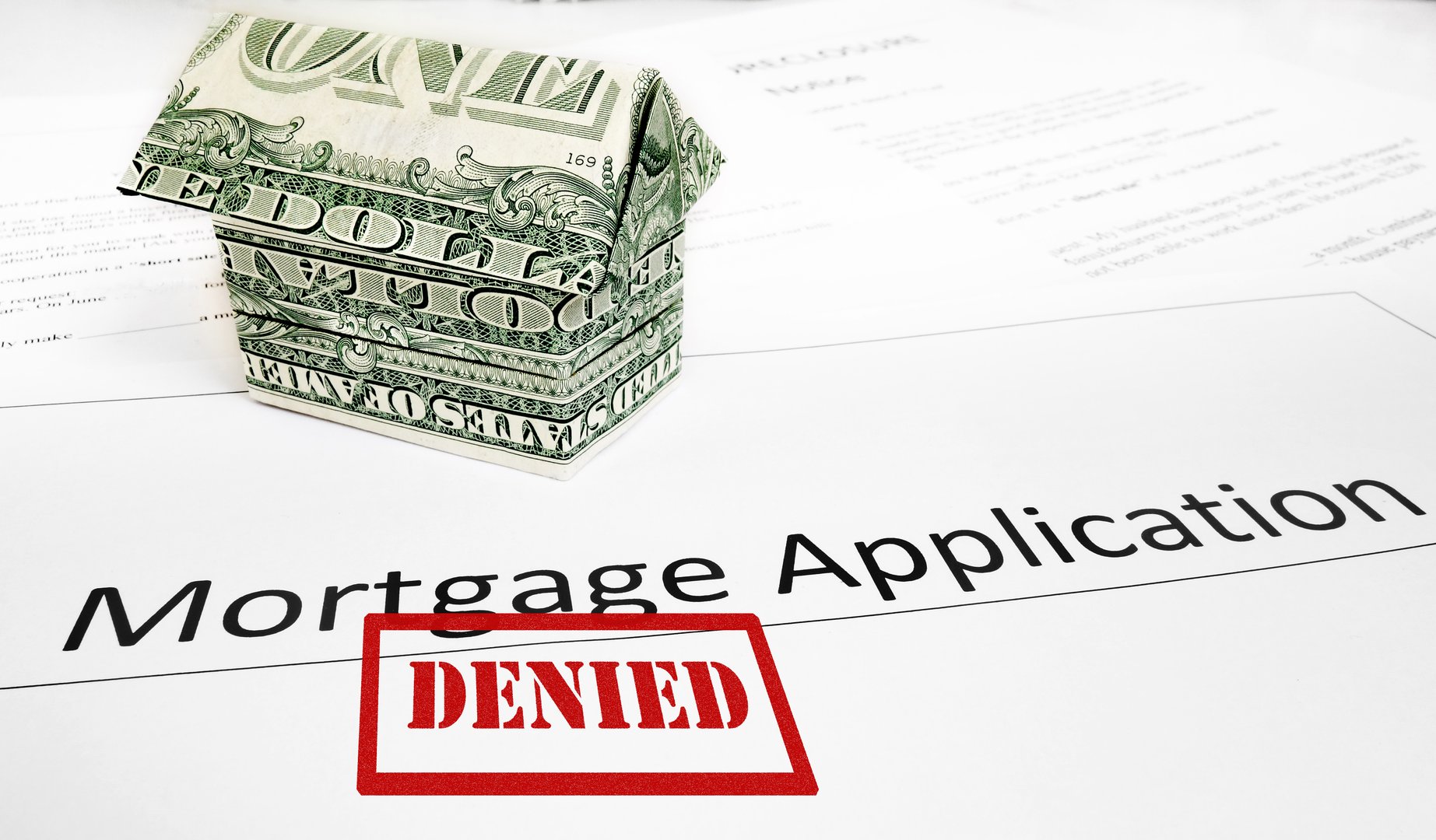 A Denied mortgage application with an origami dollar house