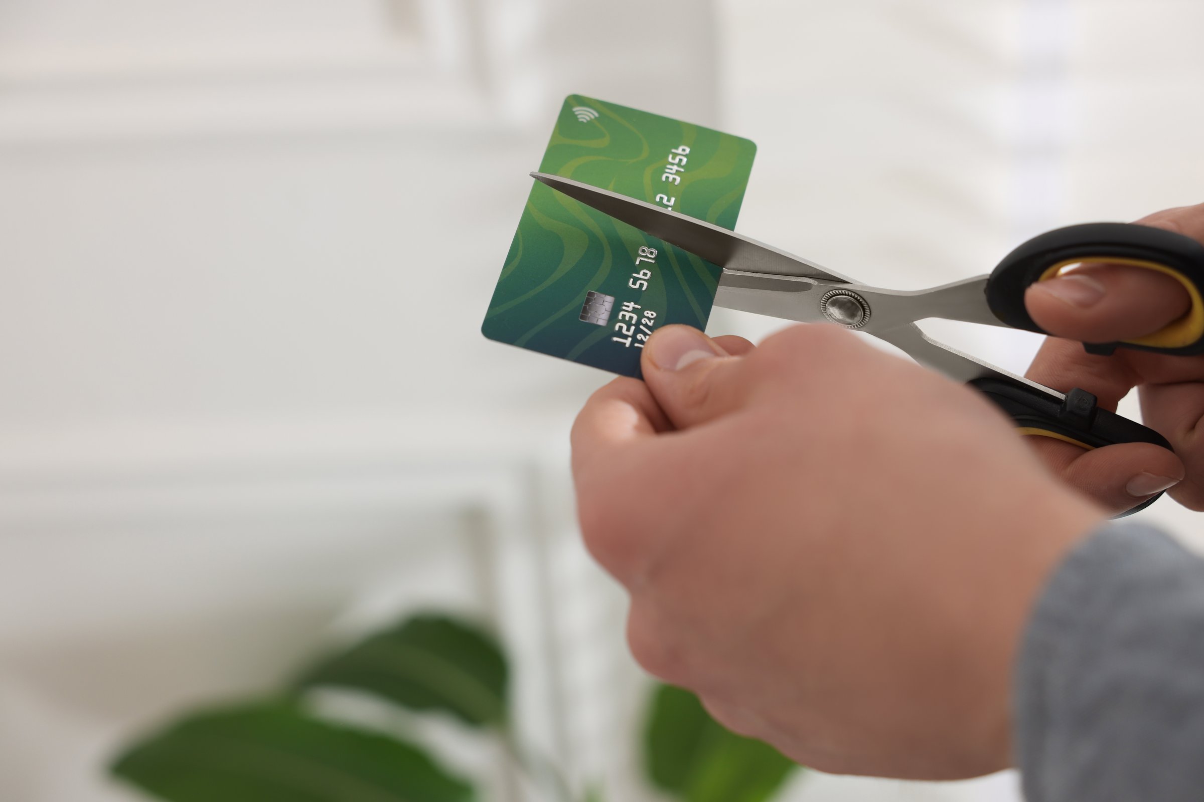 Man cutting his credit card indoors, closeup