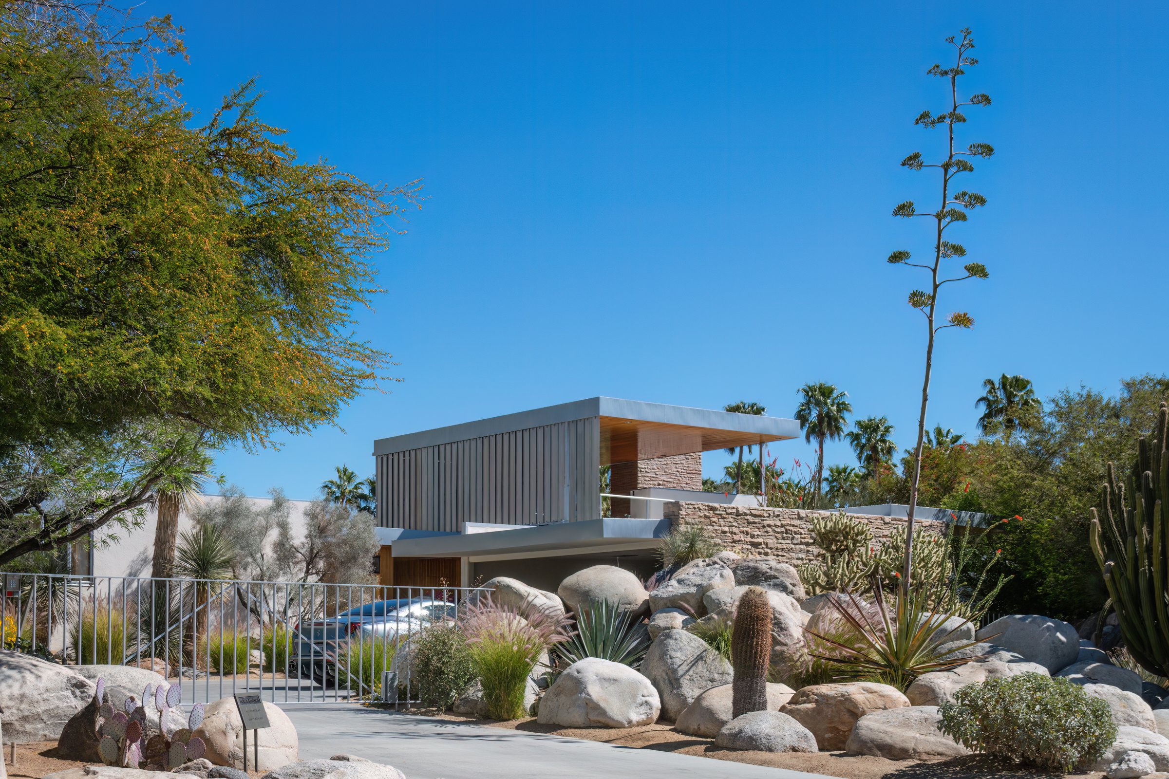 Palm Springs, California, USA - April 16, 2024: Kaufmann House. An example of mid-century modern architecture home. Architect Richard Neutra. With silver colored Ferrari against blue sky,
