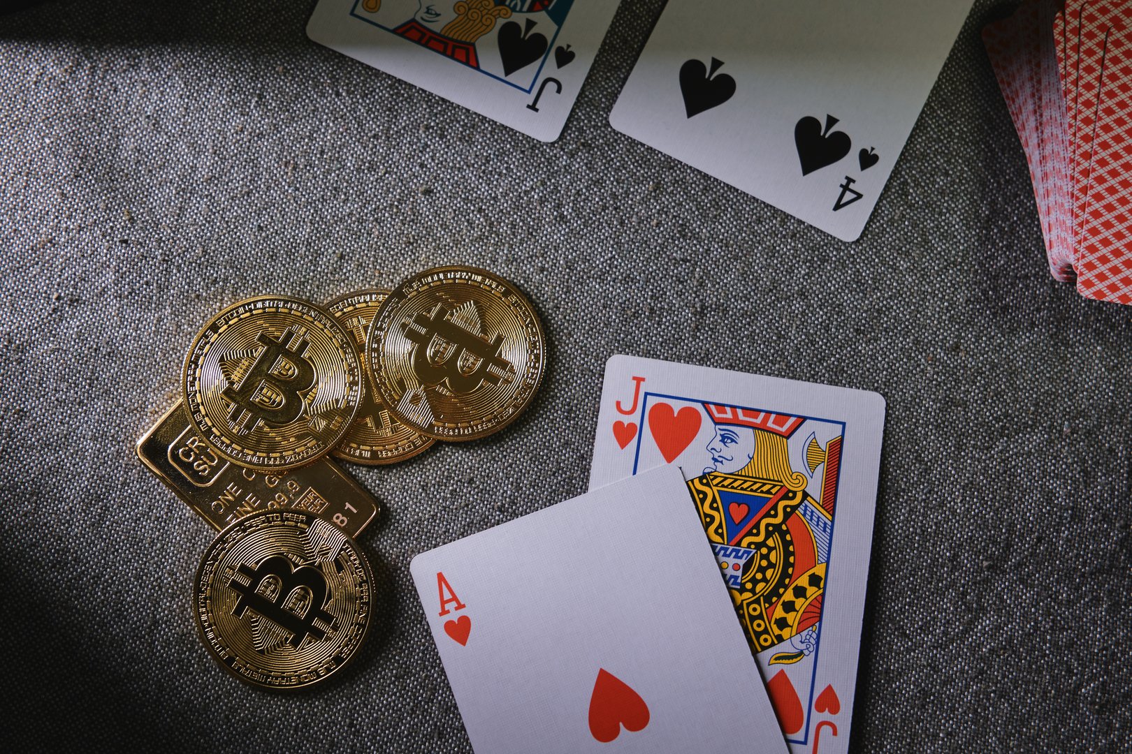 Golden bitcoin tokens and playing cards representing gambling, risk, and online casino games