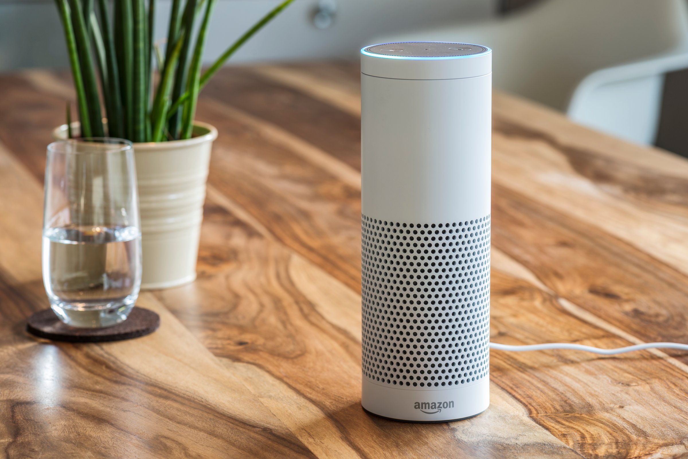 White Amazon Echo Plus Alexa Voice Service device on wooden table