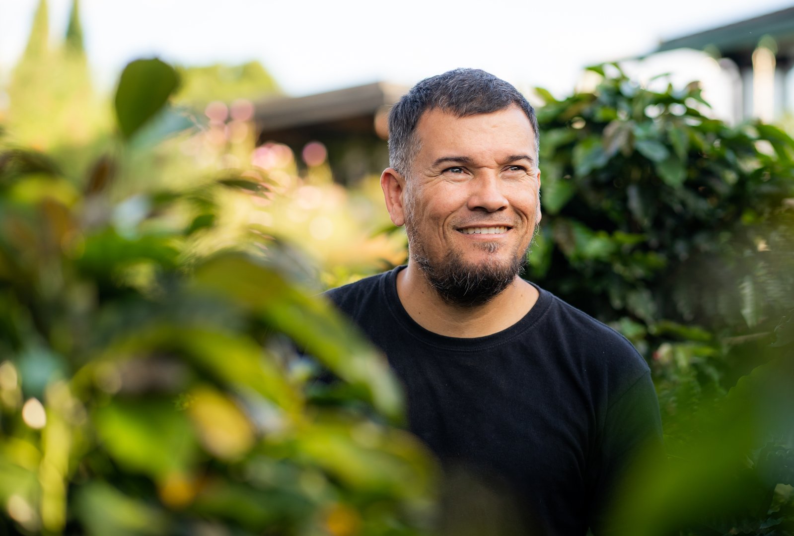 Middle-aged Latino man smiling and looking to the side outdoors.