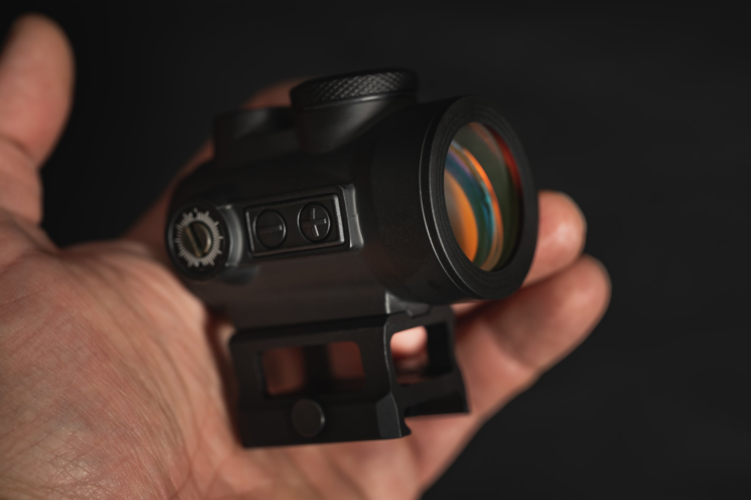 A modern red dot sight in a man's hand, close-up photo. High quality photo