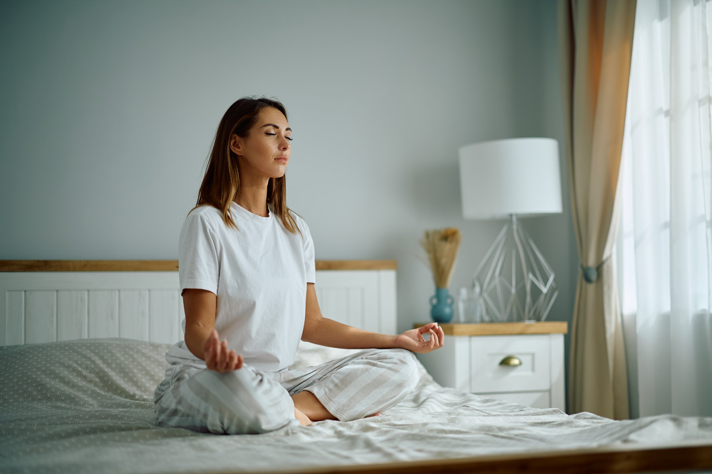 Young woman meditating with eyes closed in the morning. Copy space.