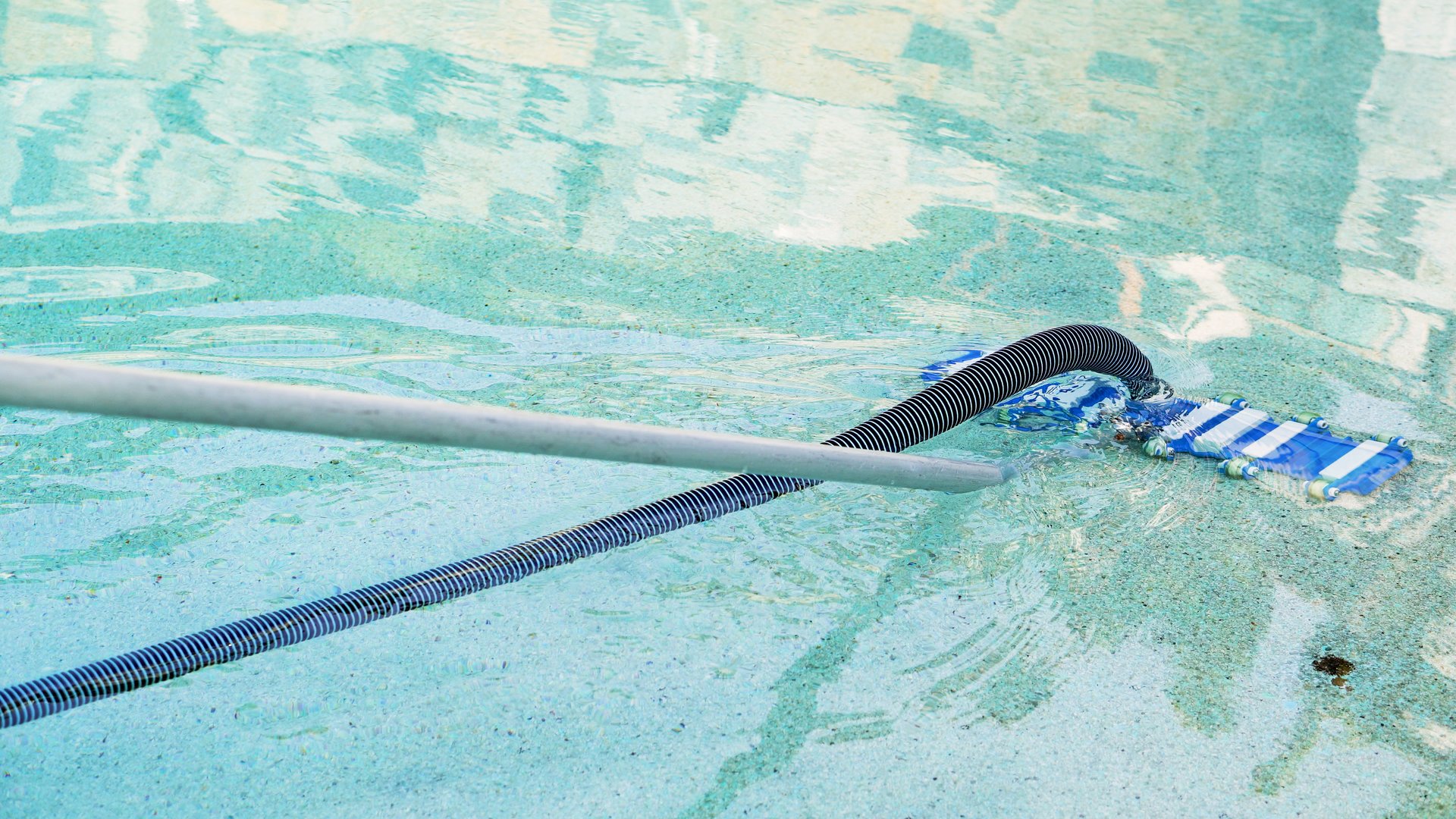 Hotel staff clean the swimming pool in the morning.