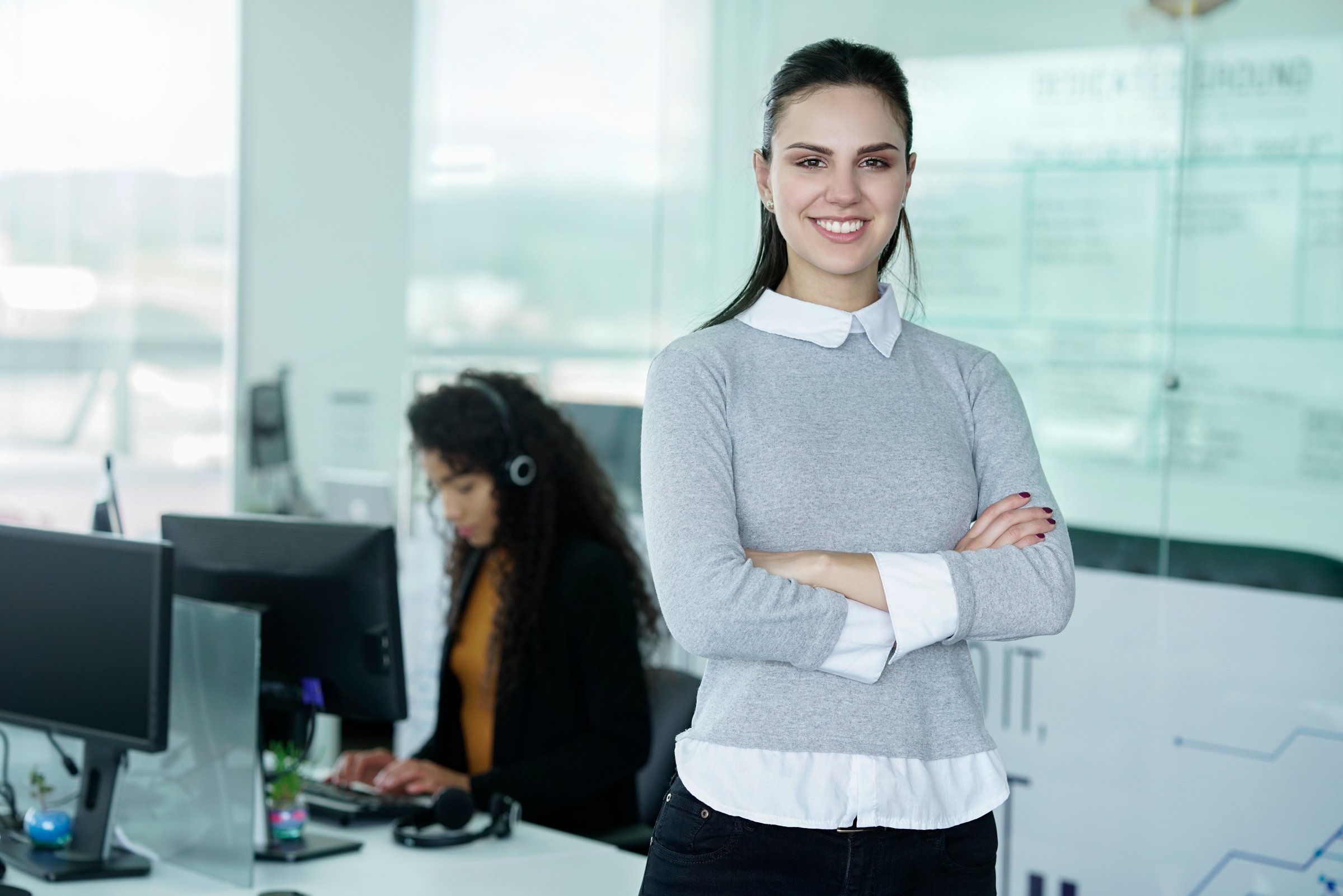 young latino businesswoman of short hair between 22 to 32 years with glasses in the office of the call center happy for the results of the positives of the company, pointing to the camera