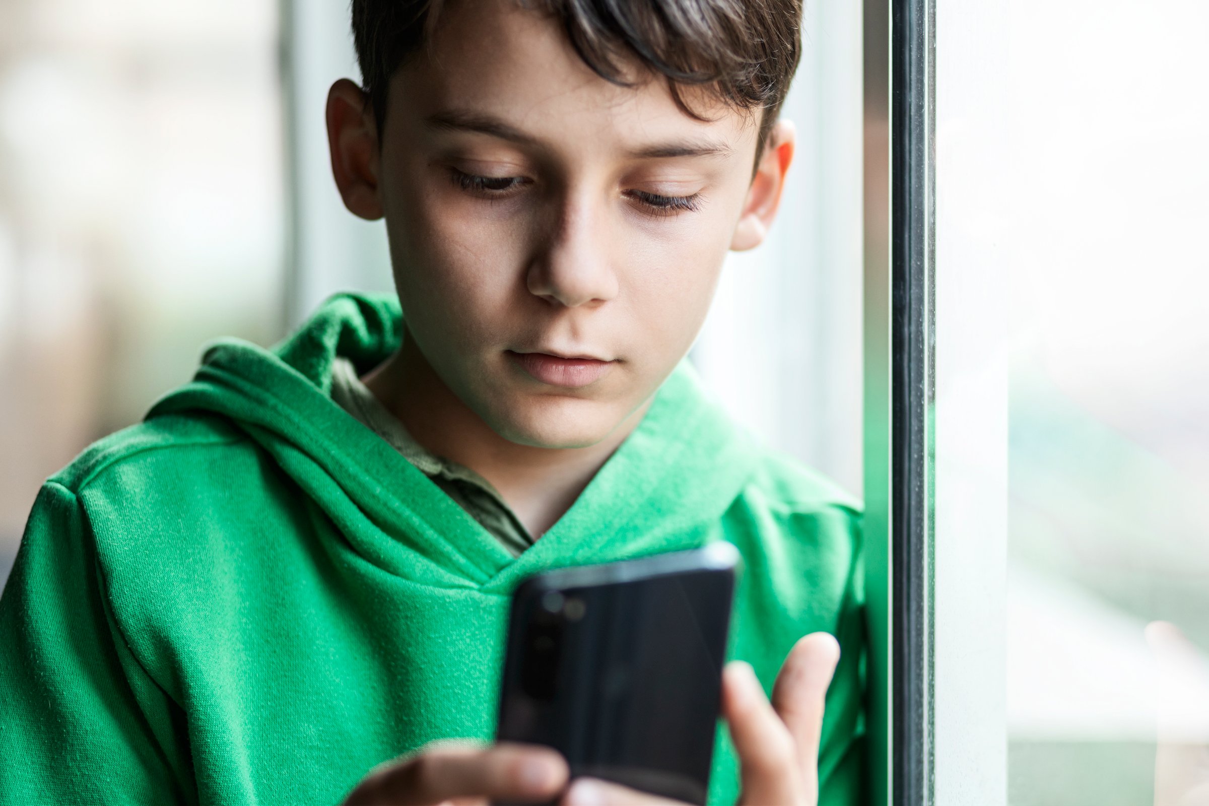 Boy with smartphone indoors. Preteen boy using a phone checking social media. Concept of children using the smartphone