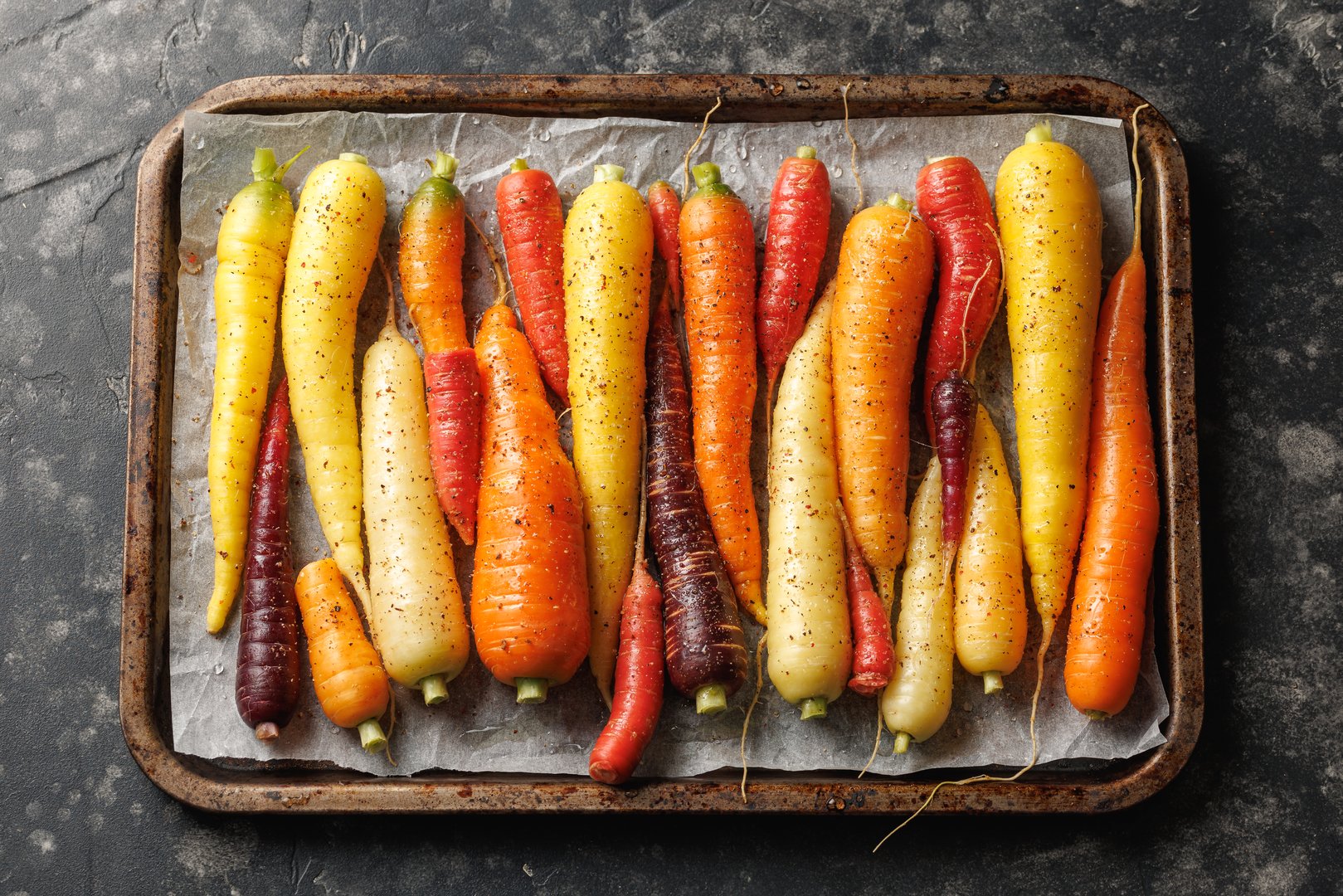 Ready to bake rainbow carrots on a parchment lined baking sheet