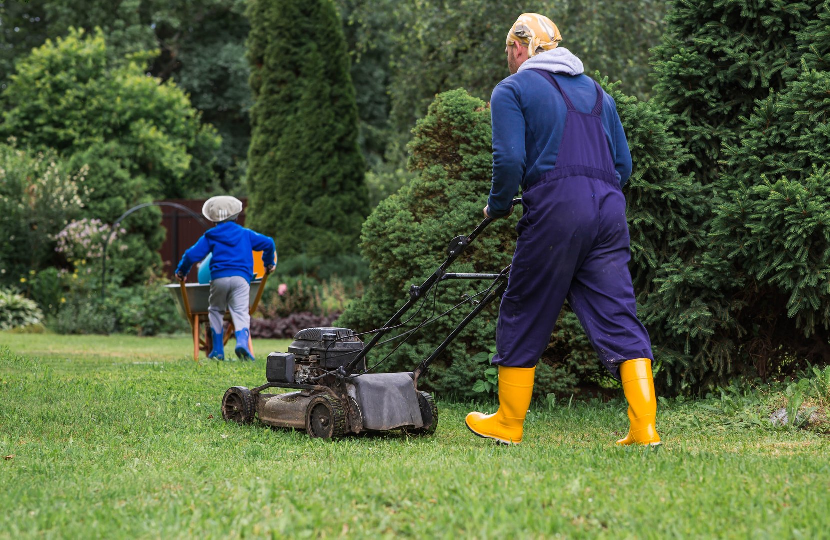 A lawn mower man mows the grass in the backyard. Agricultural machinery for garden maintenance. The concept of gardening and country life. The banner.