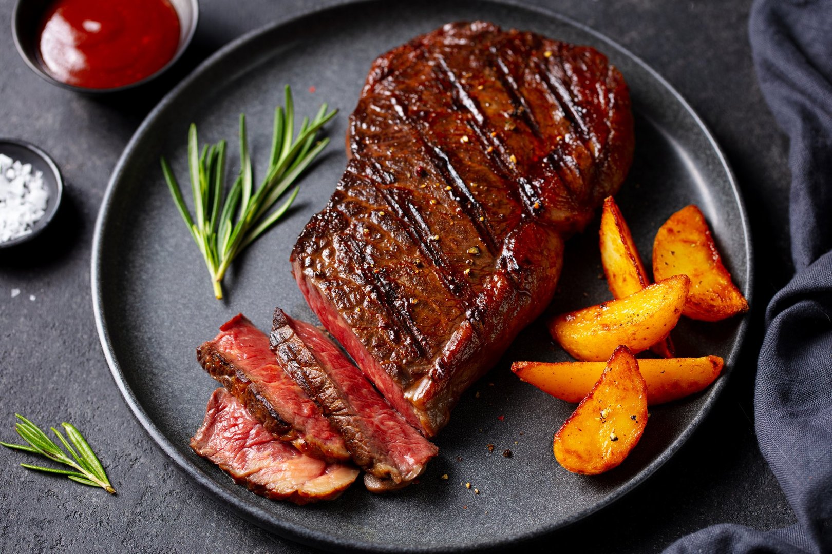 Medium rare grilled steak with roasted potato wedges and rosemary