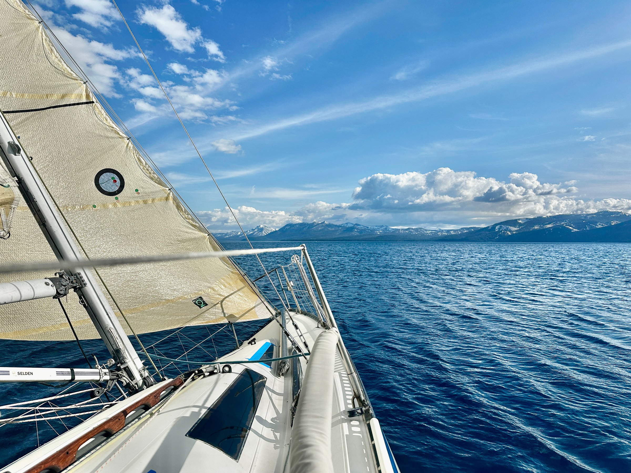 16 MAY 2025 - Lake Tahoe, CA, USA - Sailing in a small racing yacht on Lake Tahoe on the North Shore with snow capped mountains in the distance.