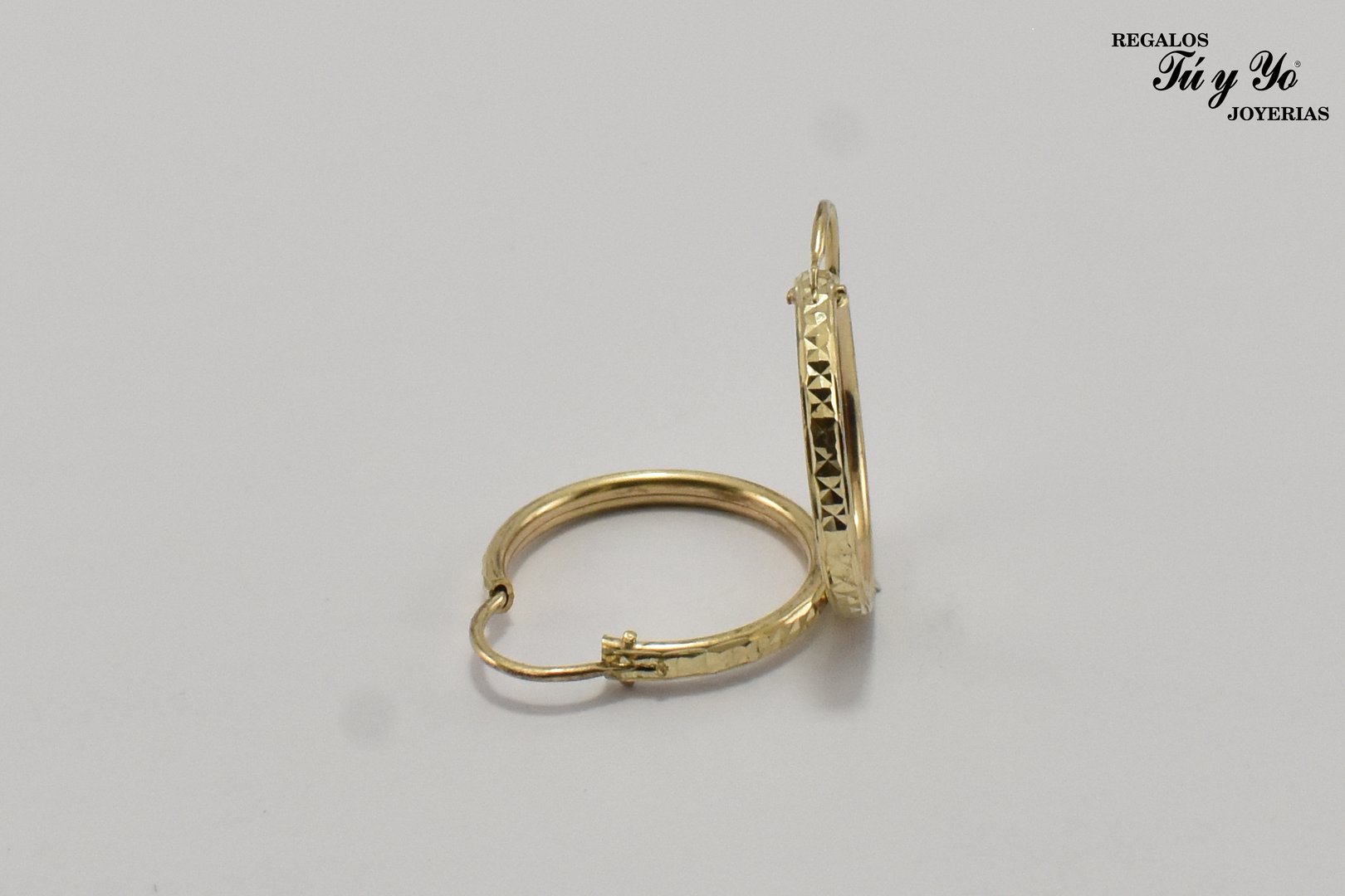 Gold hoop earrings with engraved geometric patterns, displayed on a white background.