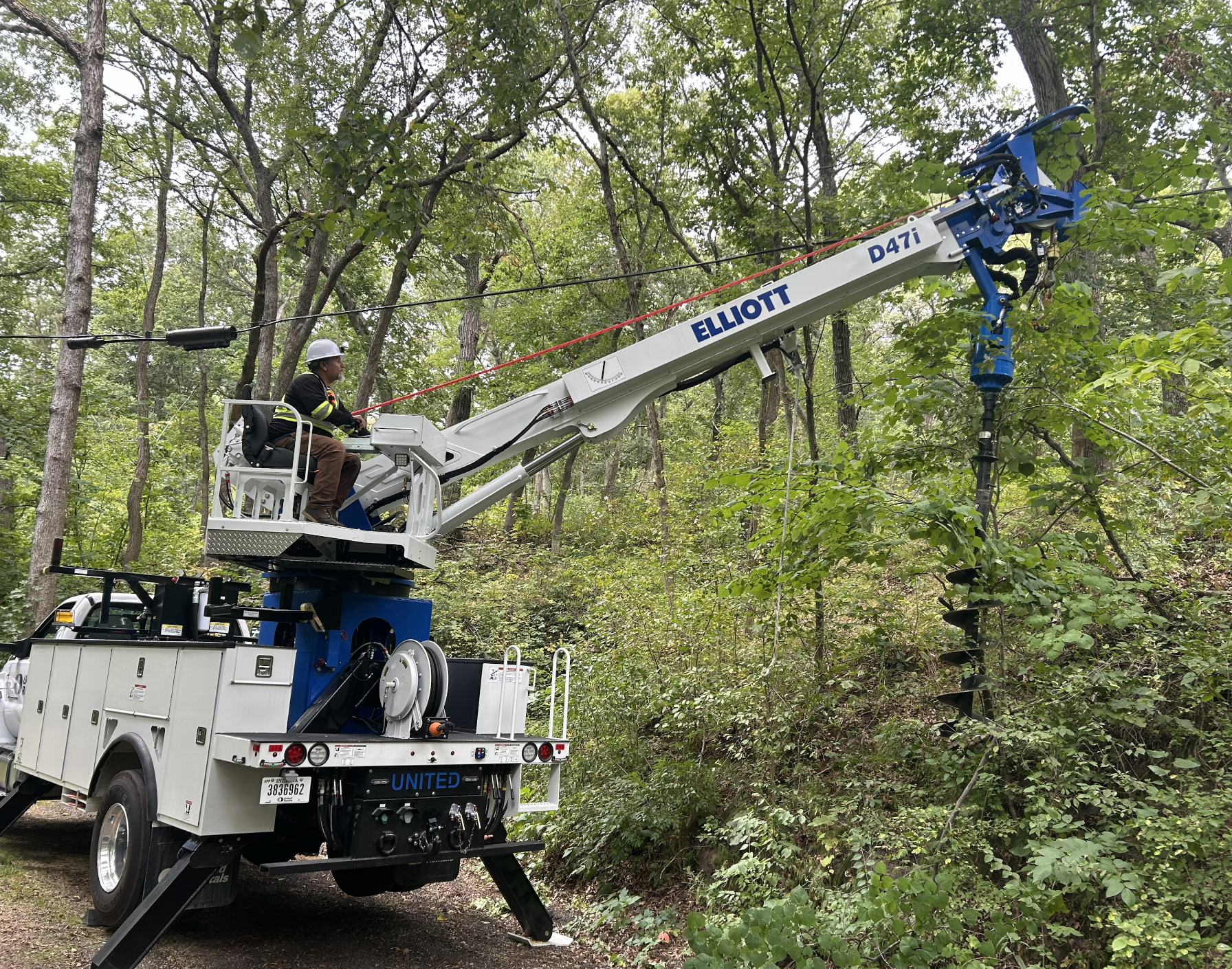 Worker in bucket lift fixes electrical components on utility pole during work day