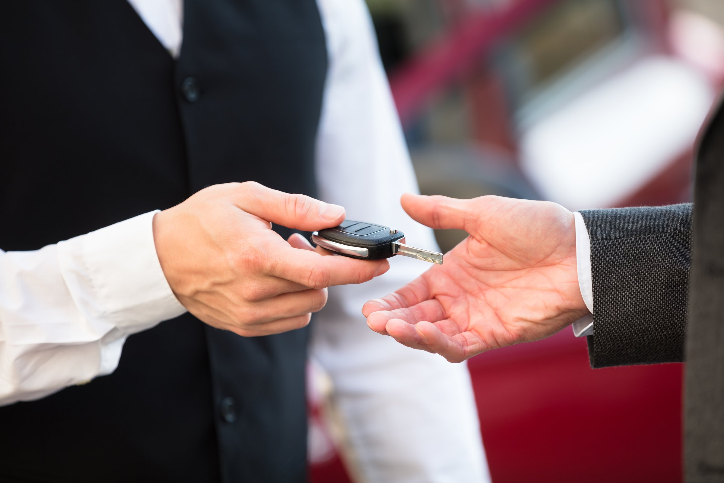 Close-up Of Valet's Hand Giving Car Key To Businessperson