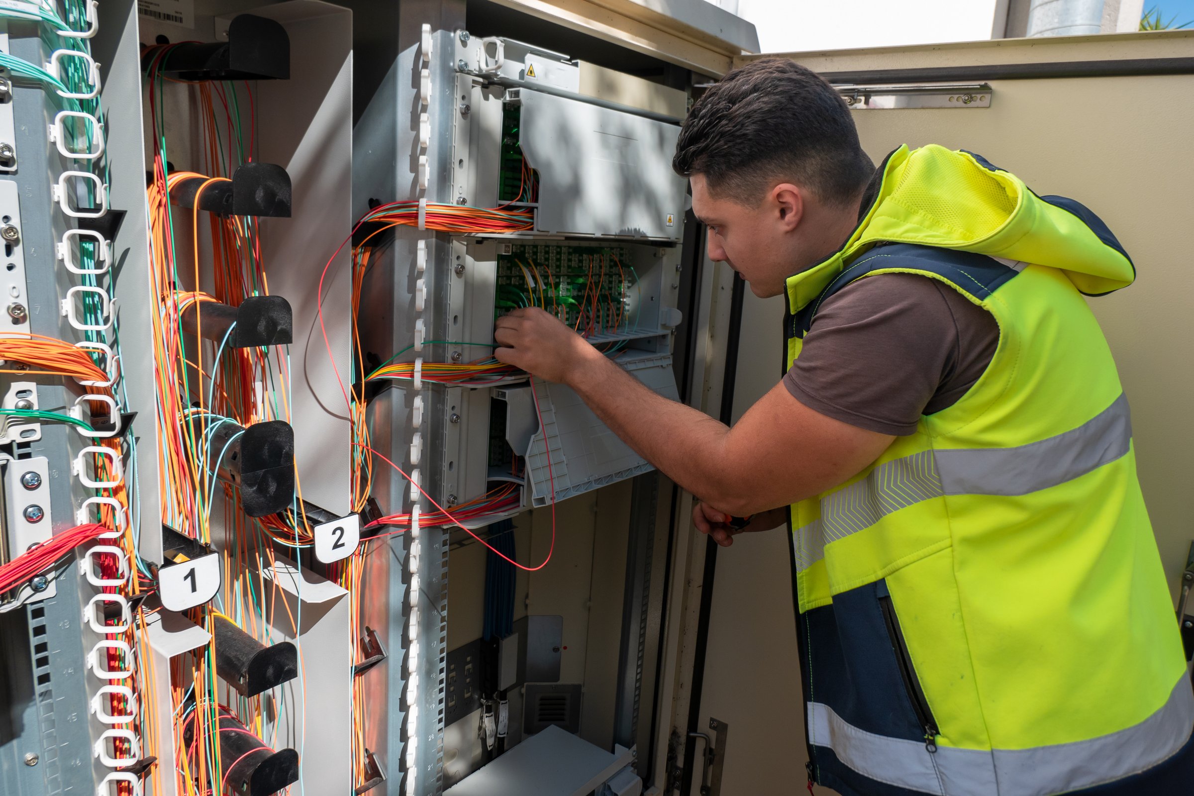 Technician performing maintenance on a fiber optic cabinet to ensure network quality for customers
