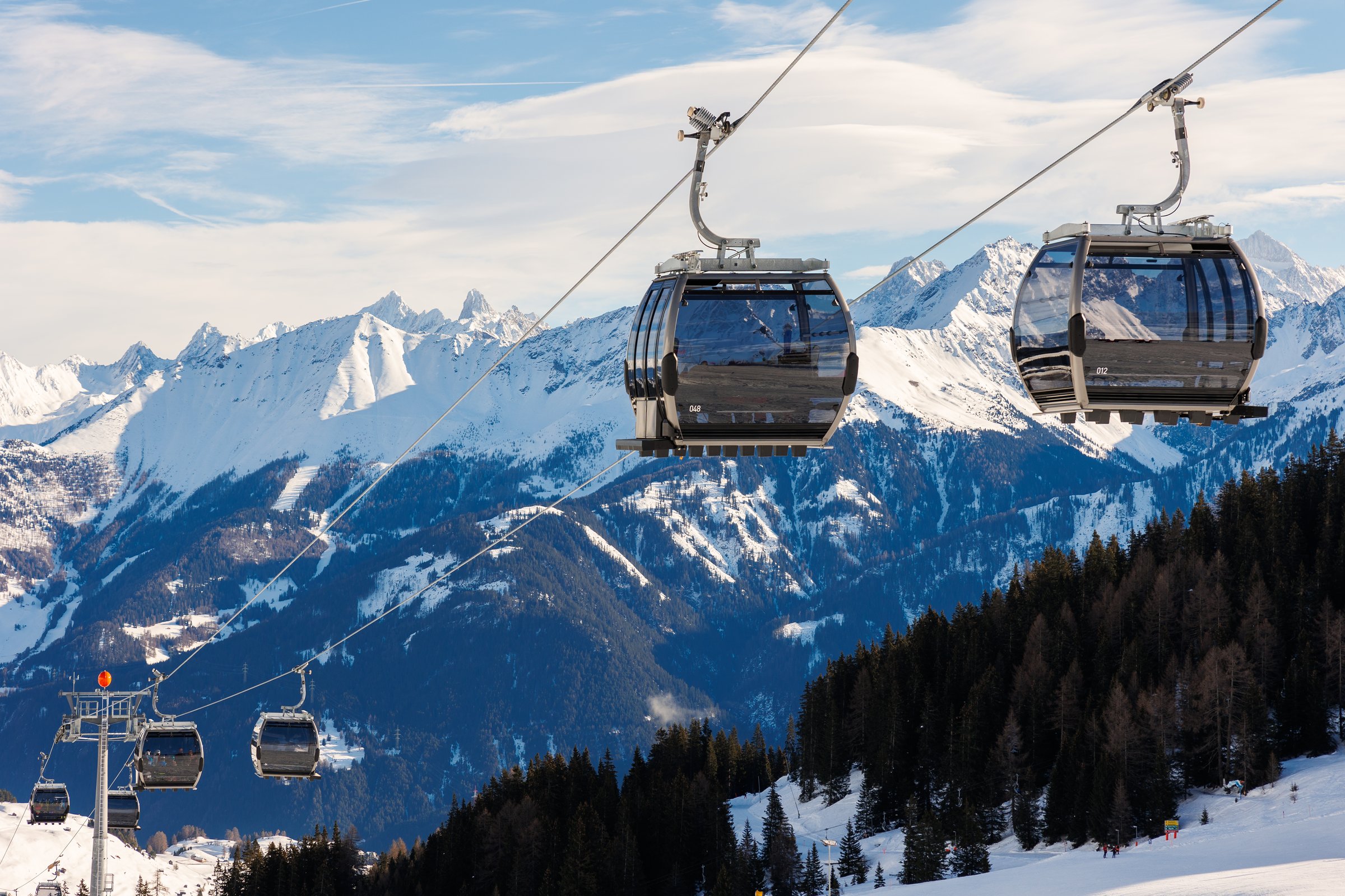 New modern spacious big cabin ski lift gondola against snowcapped forest tree and mountain peaks covered in snow landscape in luxury winter alpine resort. Winter leisure sports, recreation and travel.