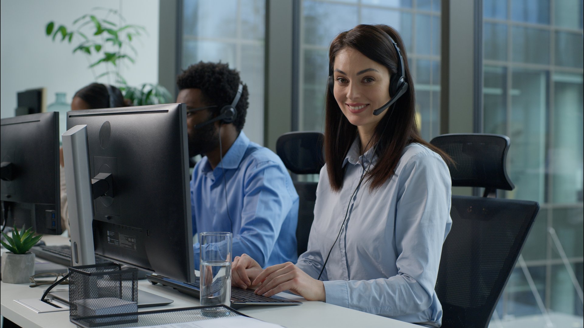Helpline callcenter multiethnic business workers working online computer office customer service call center diverse smiling Caucasian Indian women African man in headset speak work pc helping client. High quality 4k footage