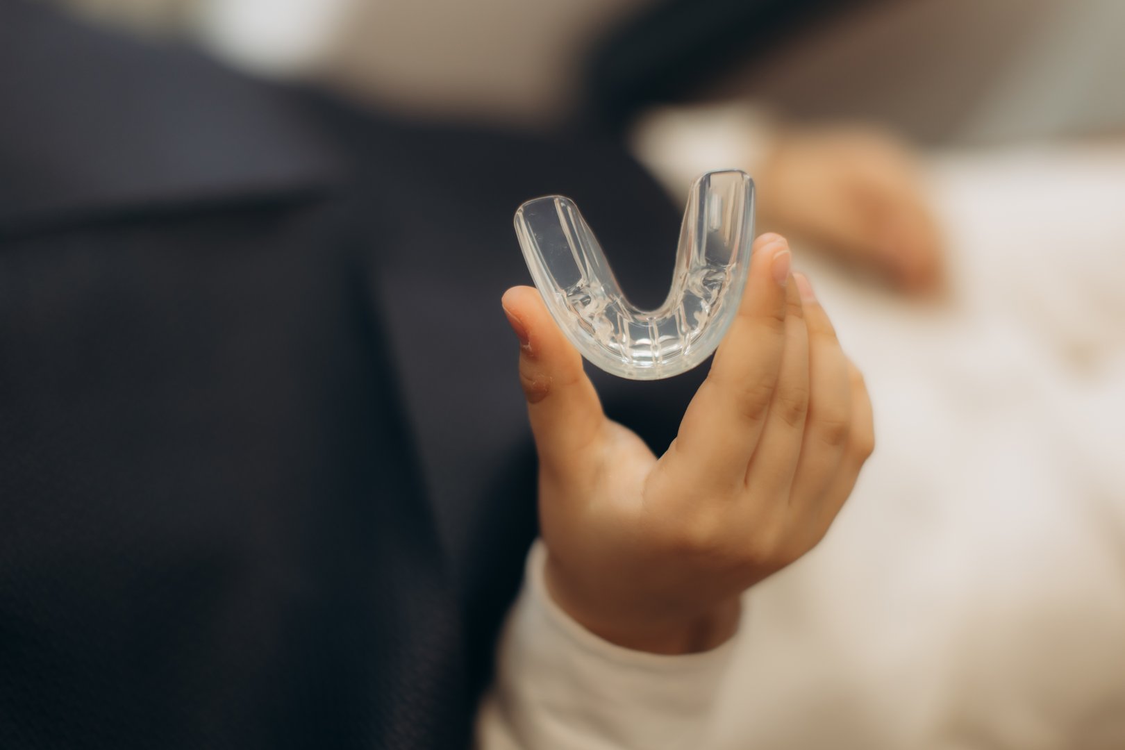 Hand holding transparent dental guard for teeth protection