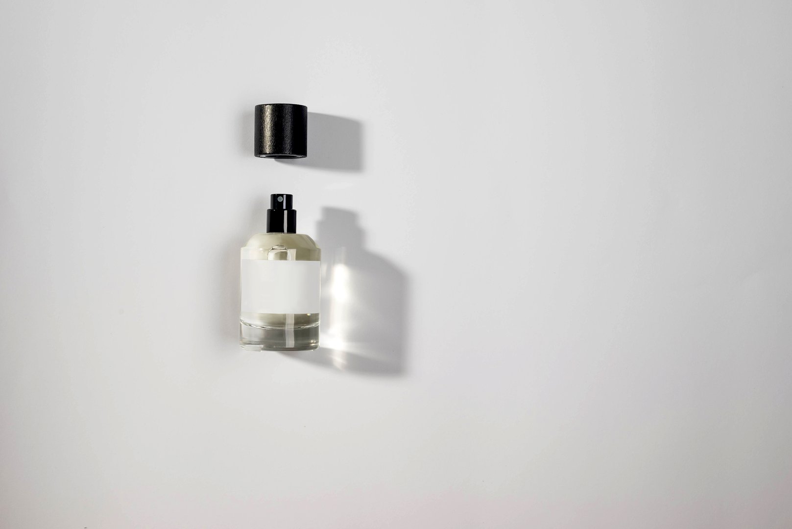 sleek perfume bottle with a black cap, set against a white background. The clean lines and elegant design create a luxurious and inviting aesthetic,