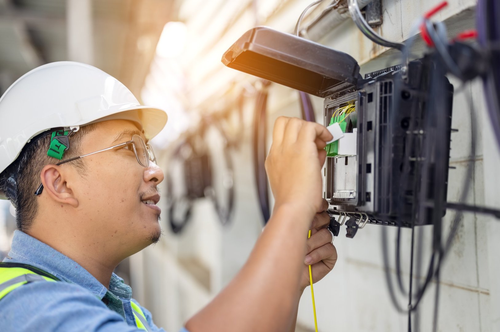An internet technician is repairing or maintaining a fiber optic connection by opening a fiber optic connector.