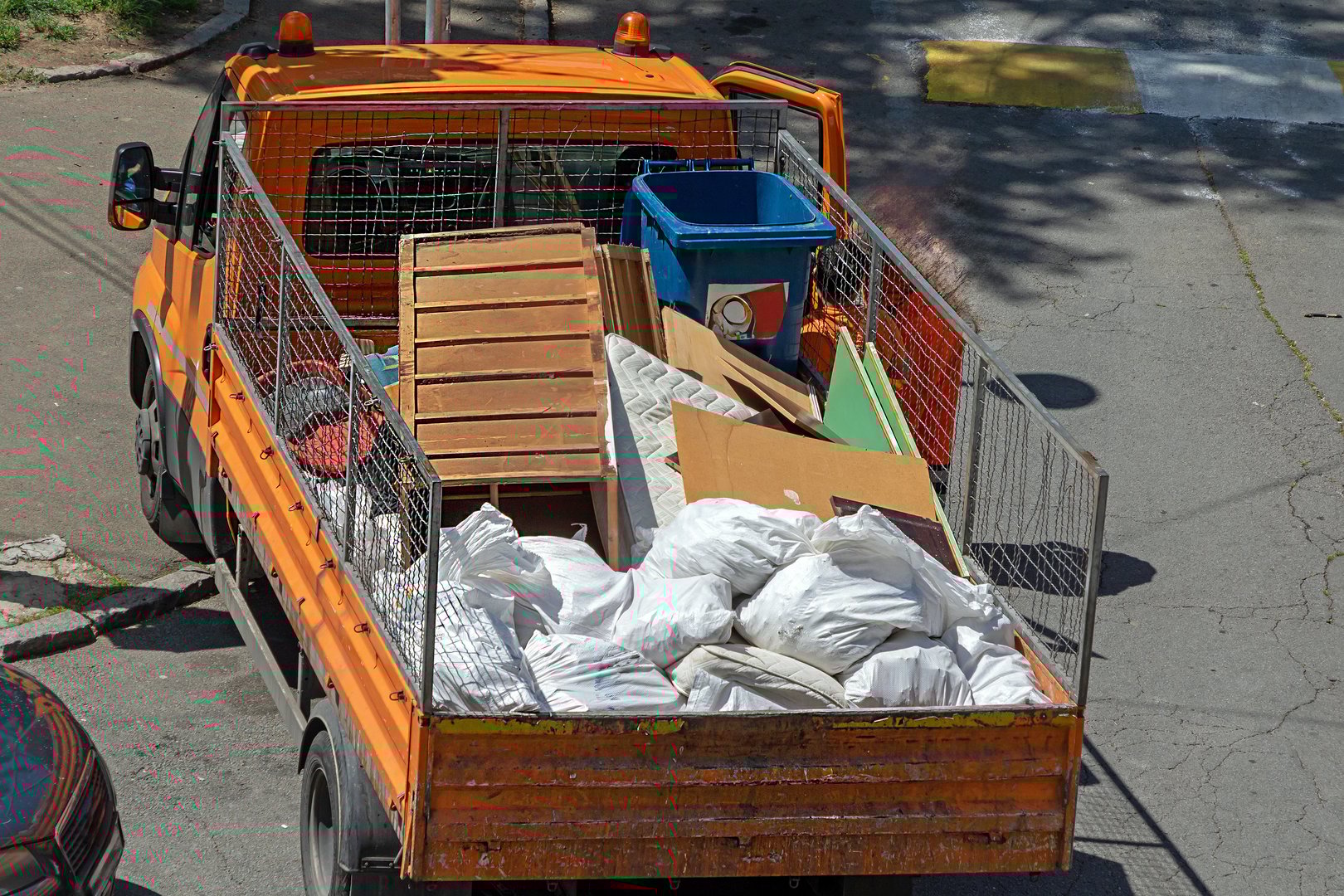 Tup truck with open back and pile of garbage picked from the street