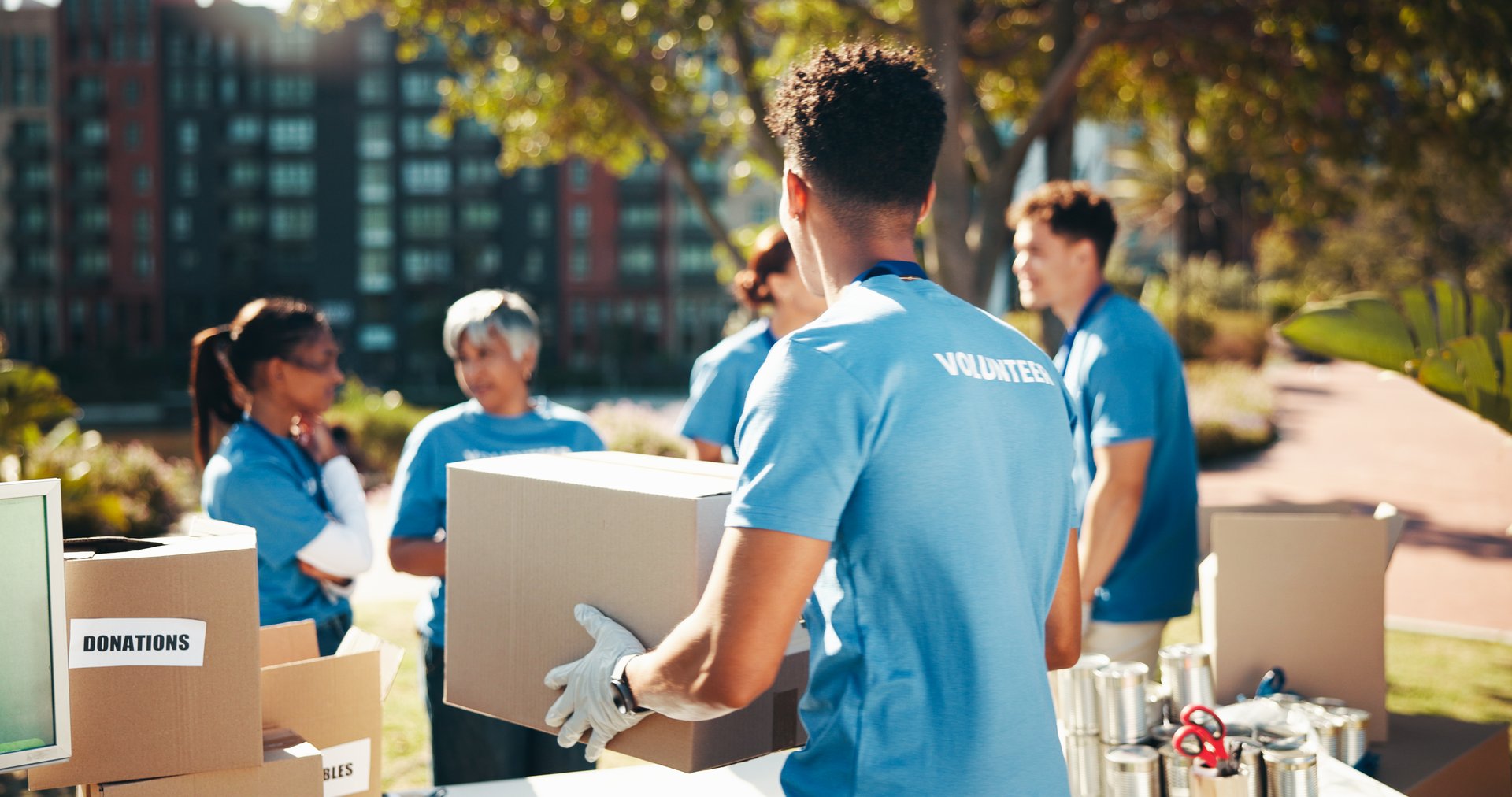 Box, volunteer team and outdoor for donation, help and back for community care. NGO group, man and charity service with package for distribution, food drive and humanitarian aid with poverty supplies