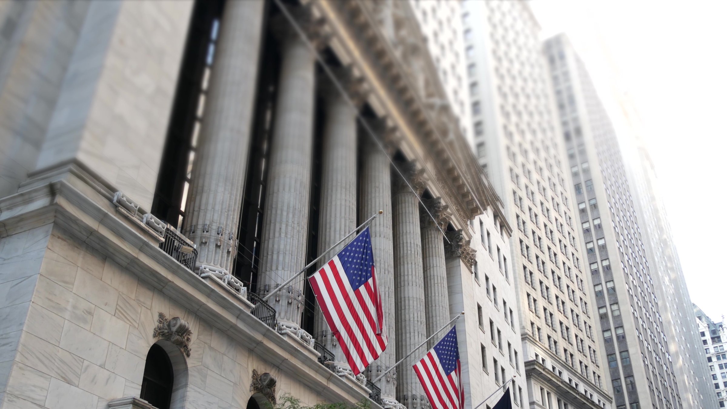 New York City, United States. Lower Manhattan Downtown Financial District urban architecture exterior. American flag. Wall street Stock Exchange building facade columns, USA Stock Market trading, NYC.