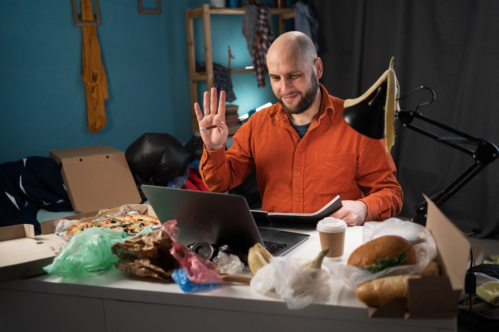 Man on remote work or online education, using laptop computer, having video call at home at daytime. Working in messy dirty room. Online business at workplace. Working from home.