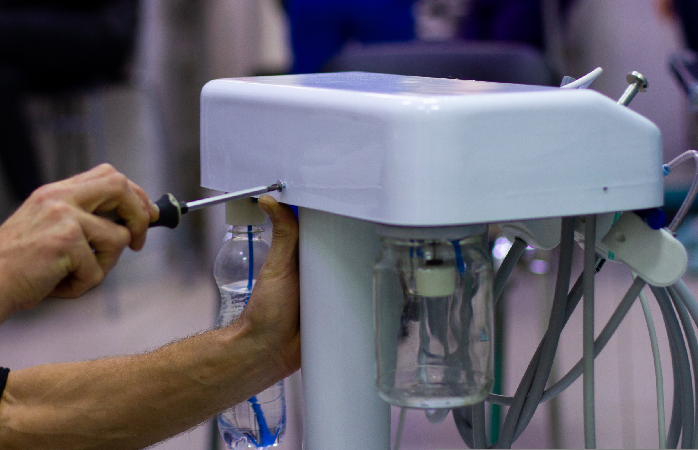 The master tightens the bolts with a screwdriver on the body of the medical oxygen apparatus. A professional mechanic repairs medical equipment in a hospital..