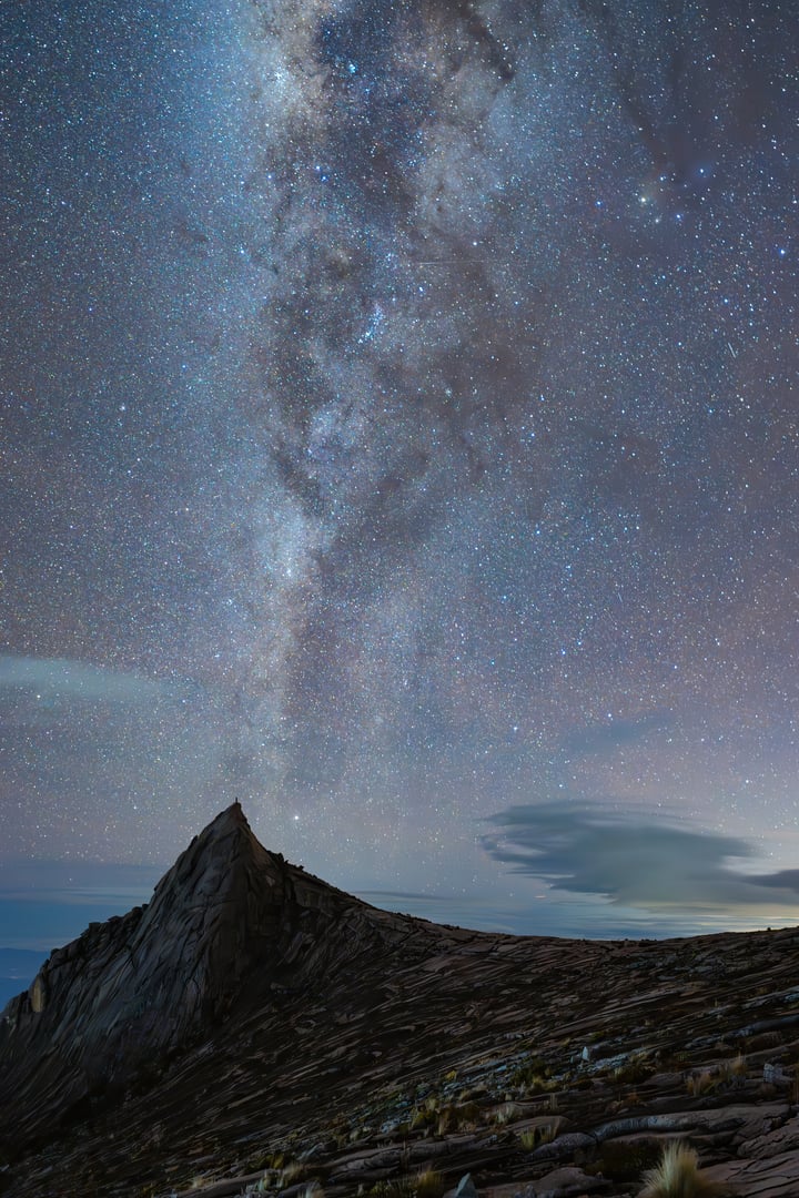 Starry night sky above a dark brown mountain