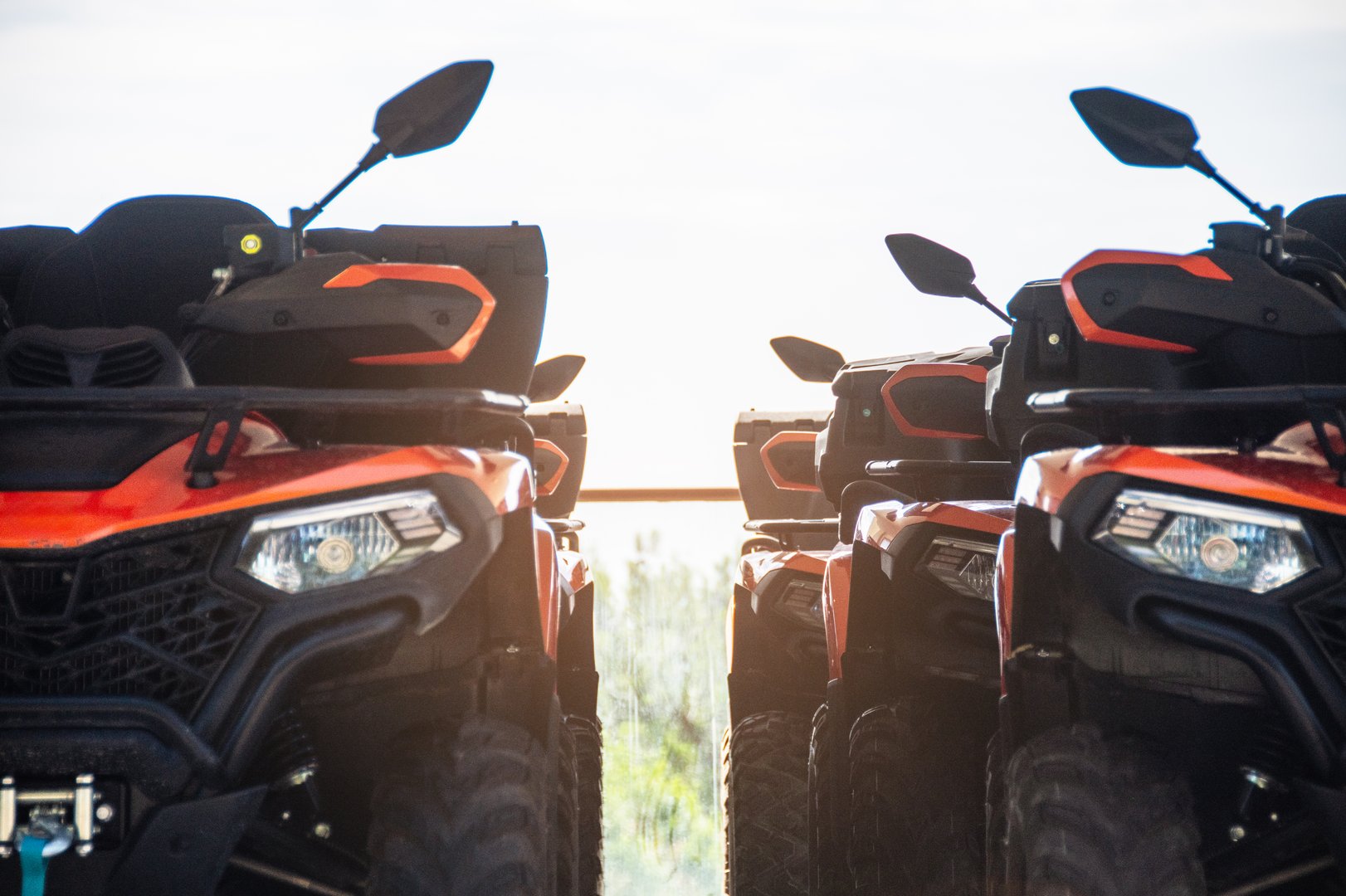 Two red and black all-terrain vehicles designed for rugged landscapes, captured at sunset, focusing on their detailed exteriors and equipped gear, embodying the thrill of off-road adventure.