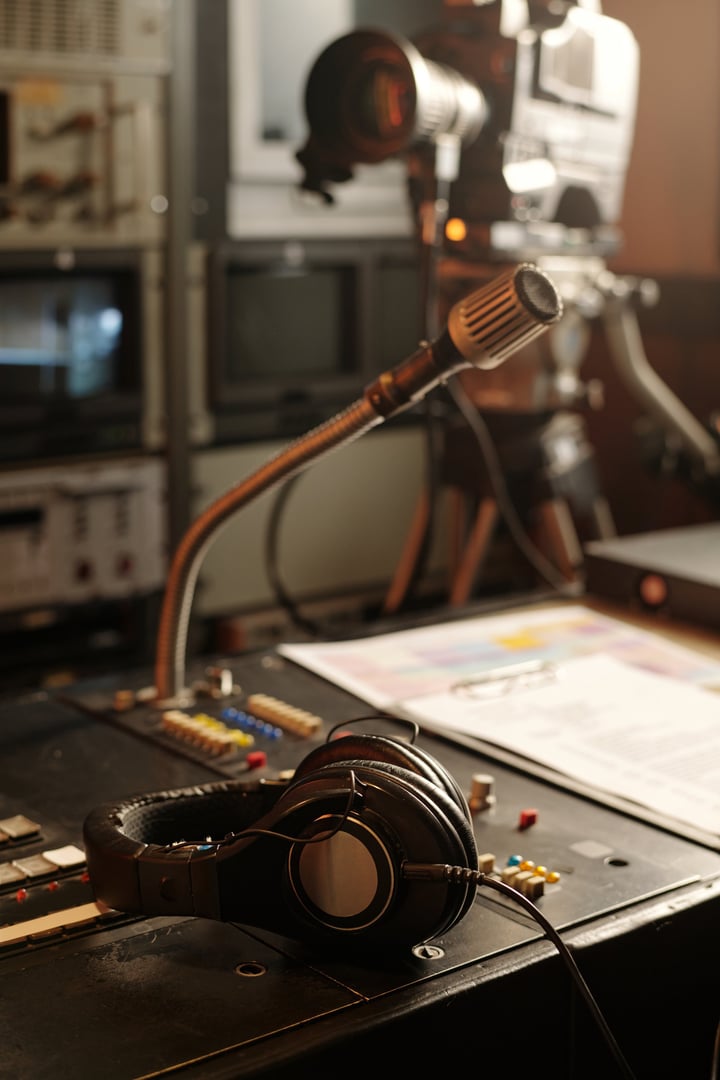 Headphones lying on sound mixing console with microphone which is workplace of modern journalist or reporter