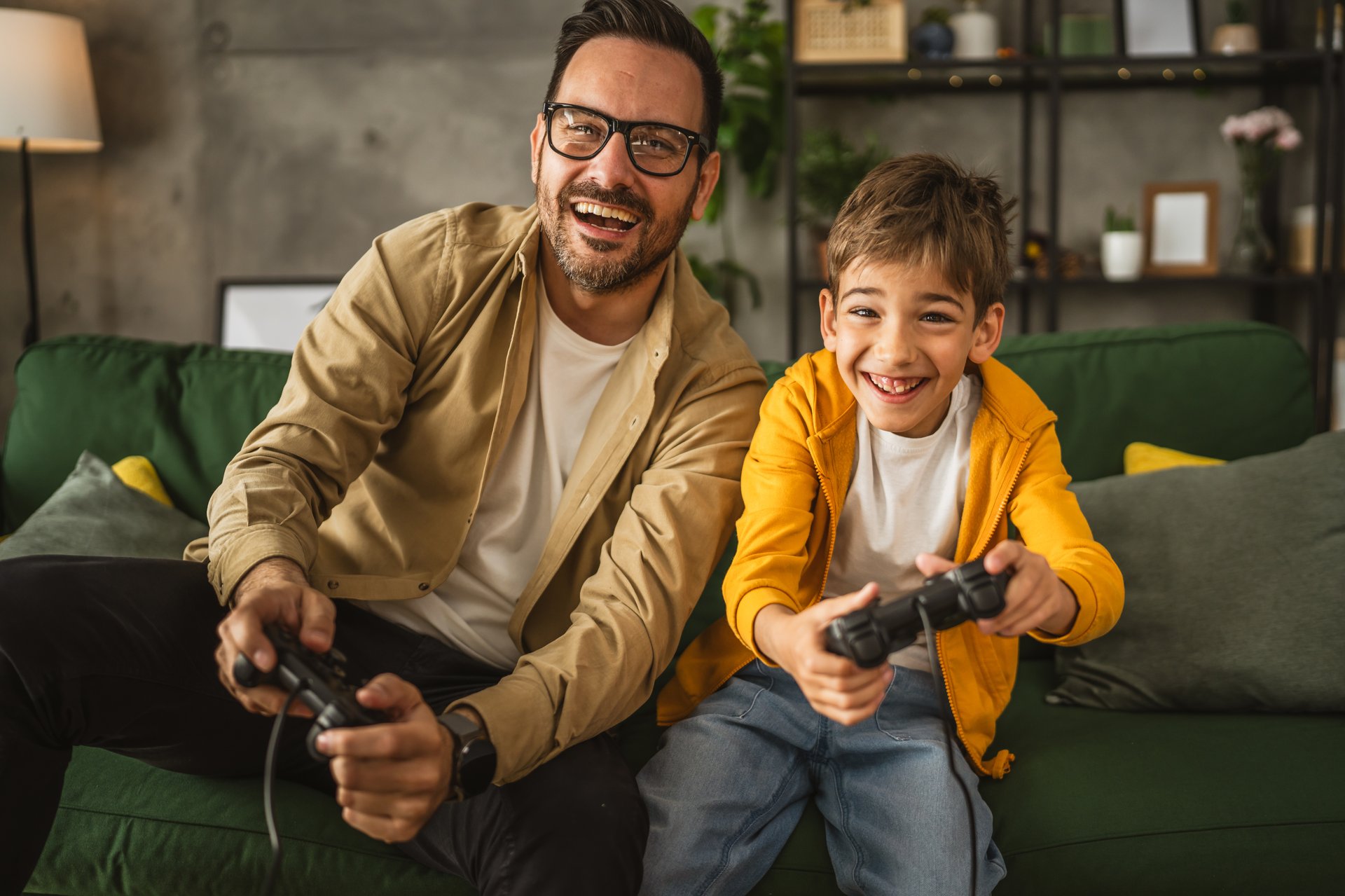 Father and son caucasian play video games with joystick and have fun at home happy enjoy
