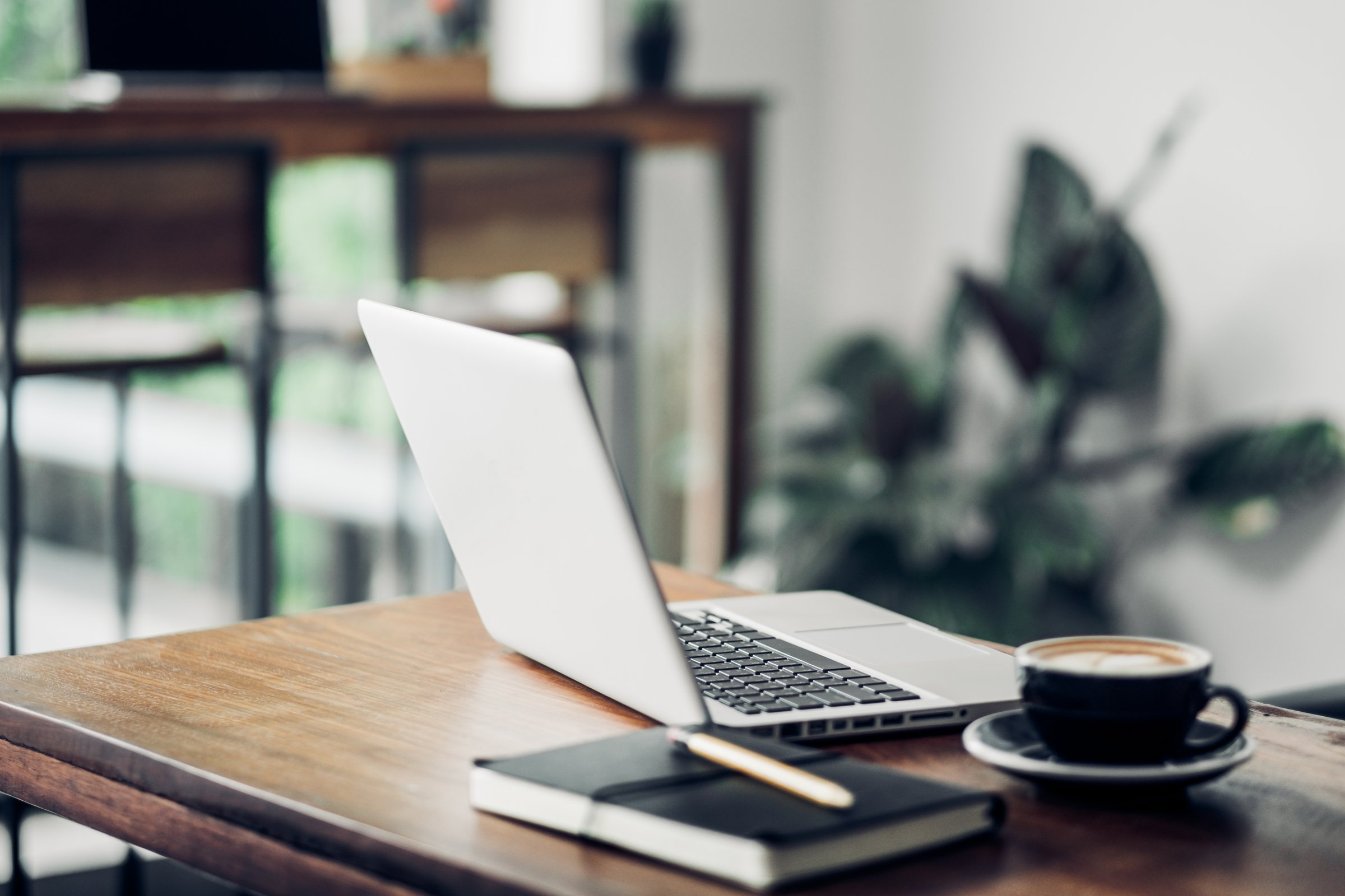 Laptop on wood table and coffee cup and notebook in cafe restaurant.