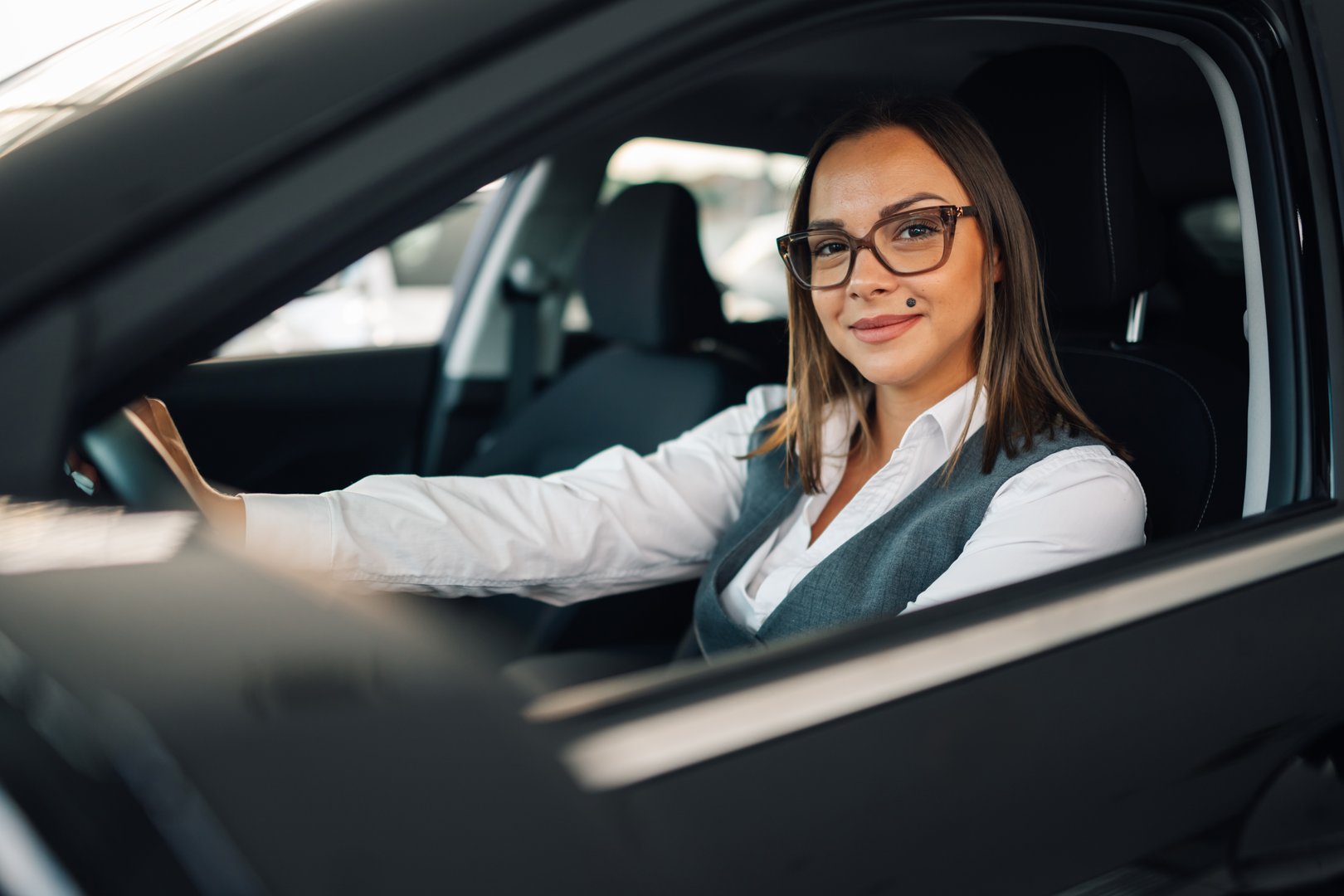 Smiling businesswoman confidently drives her modern electric car, symbolizing success and independence in her professional life
