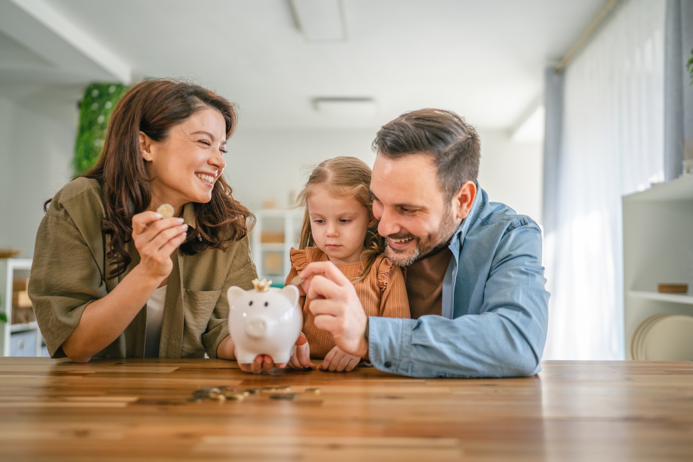 Parents teaching their young daughter about saving and responsible spending at home