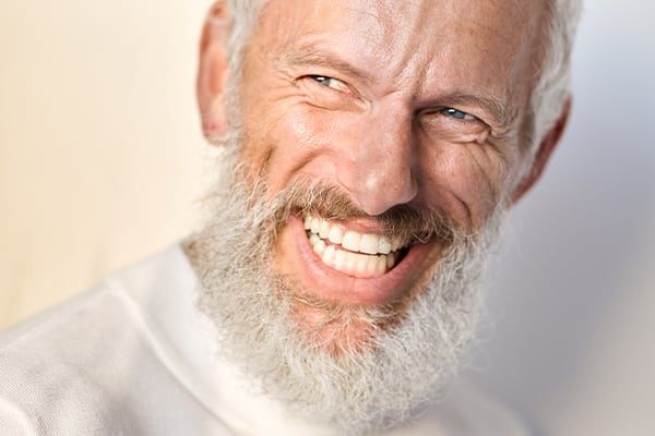 Smiling woman showcasing beautiful teeth after restorative dentistry treatment including crowns, fillings, and dental repairs