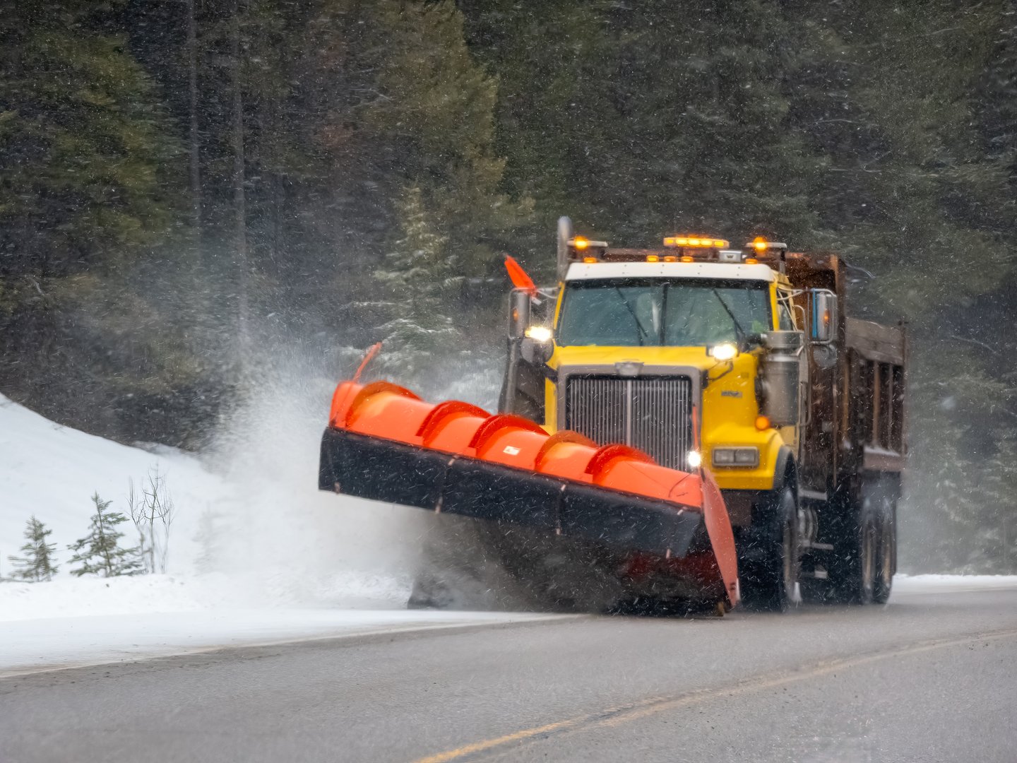 Snow plow truck clearing snow on winter road, essential for winter maintenance in Anchorage.