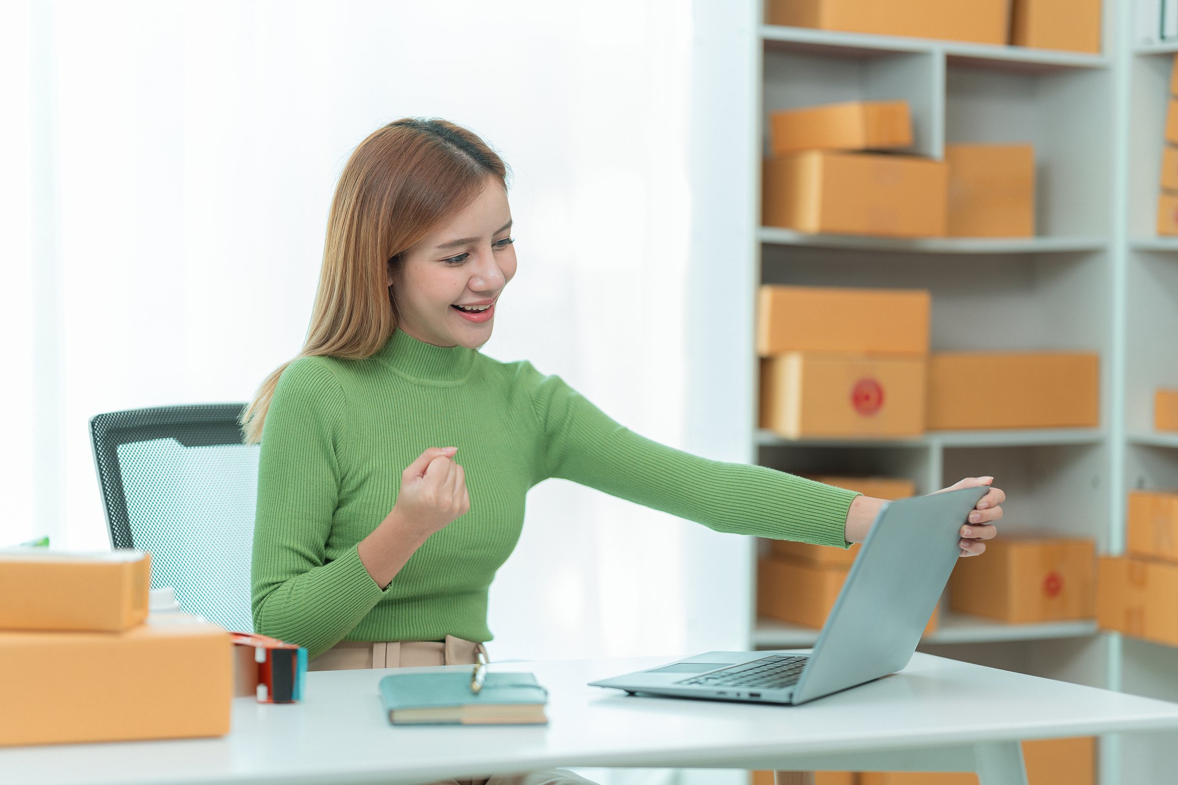 Asian woman she is excited and smiling to receive new order name size working with packaging box to write customer address in post box to send product sold online.