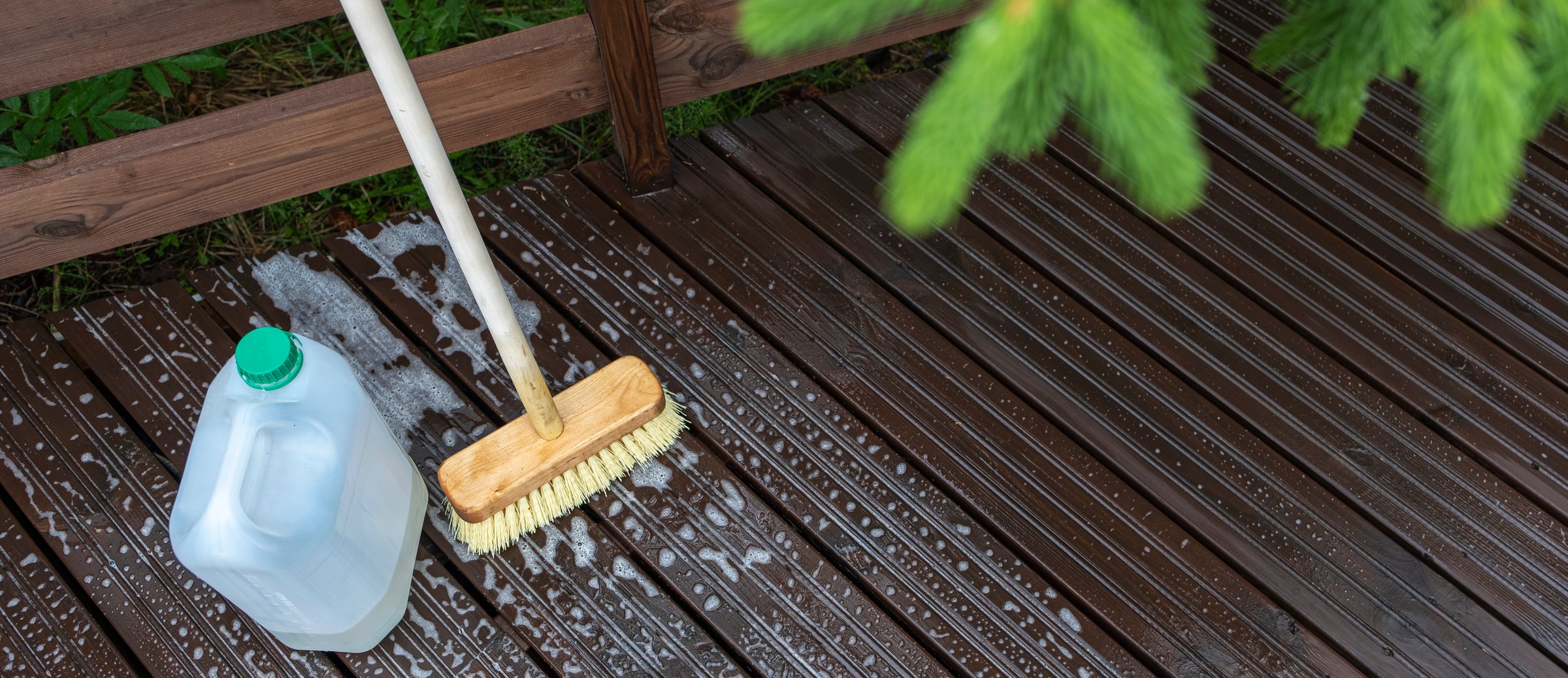 Top view. Cleaning and cleaning products, brush and canister with detergent. Soapy foam on the wooden floor of the terrace.