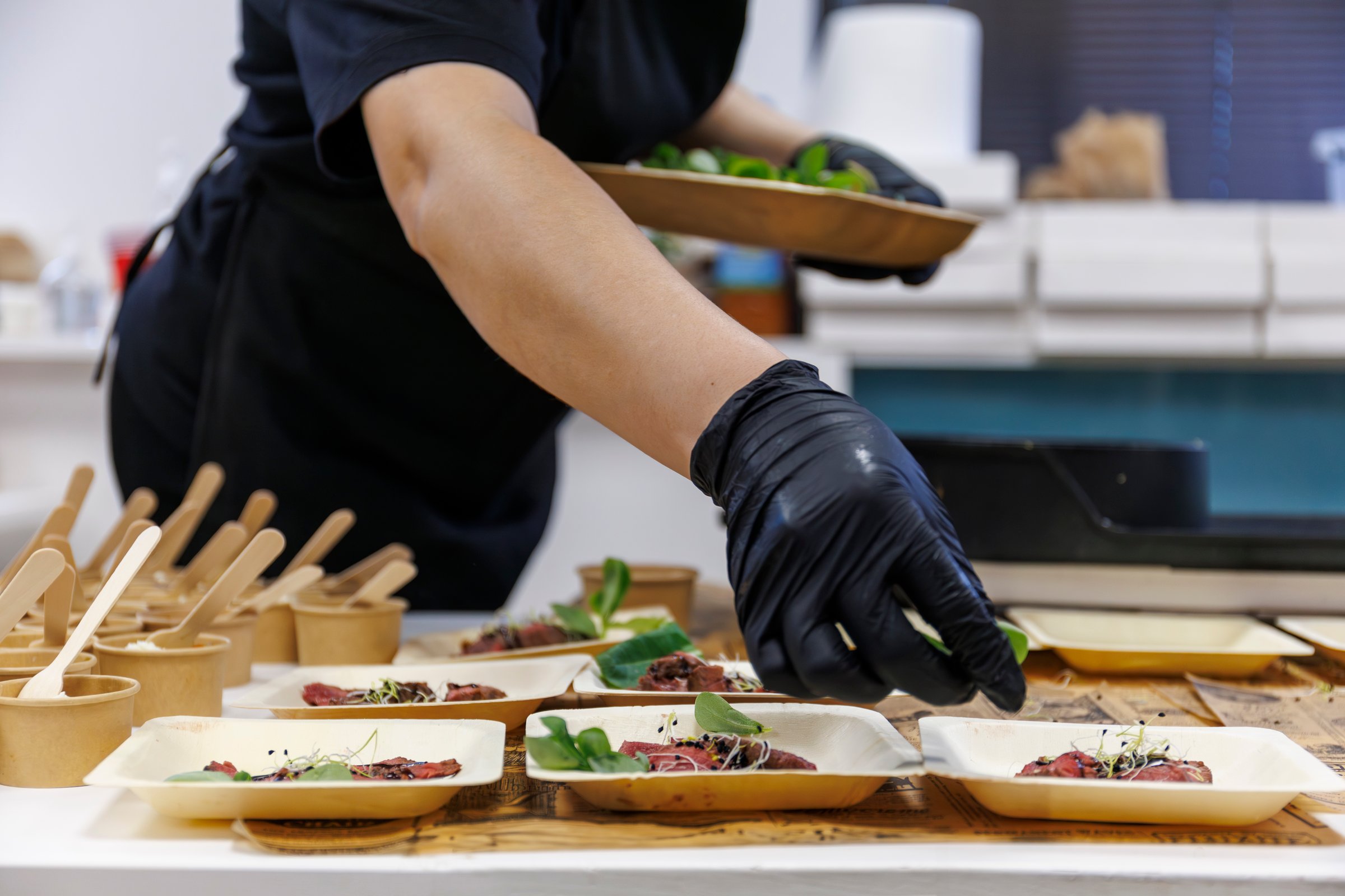 Chef emplatando bocadillos con guantes de nitrilo en evento de catering.