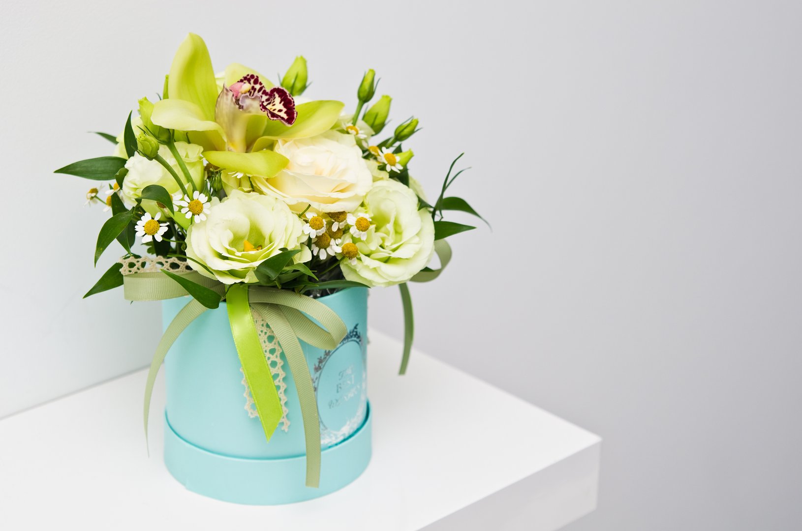 An elegant bouquet of various natural flowers in blue flower box as home decoration. Best wishes text on the box.
