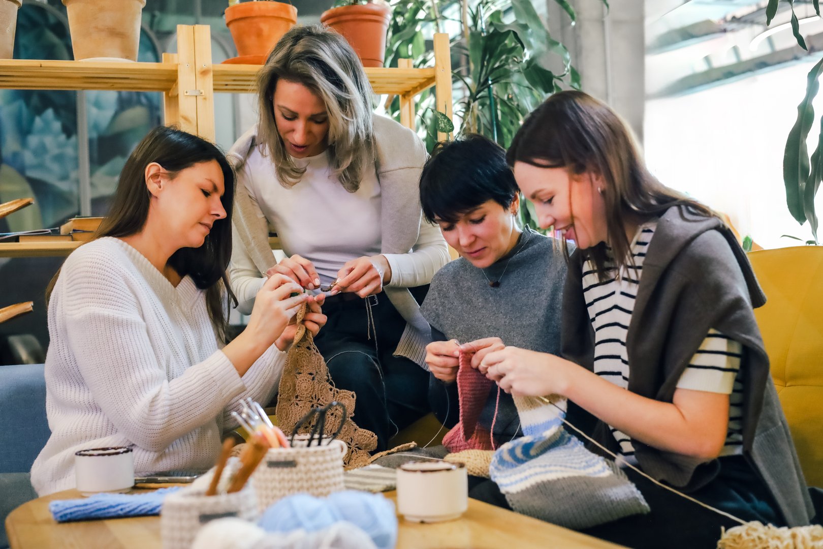 A group of women knitting together in a cozy workshop, focusing on handmade yarn crafts, creativity, and relaxation. Warm atmosphere, teamwork, and hobby enjoyment in a friendly setting.