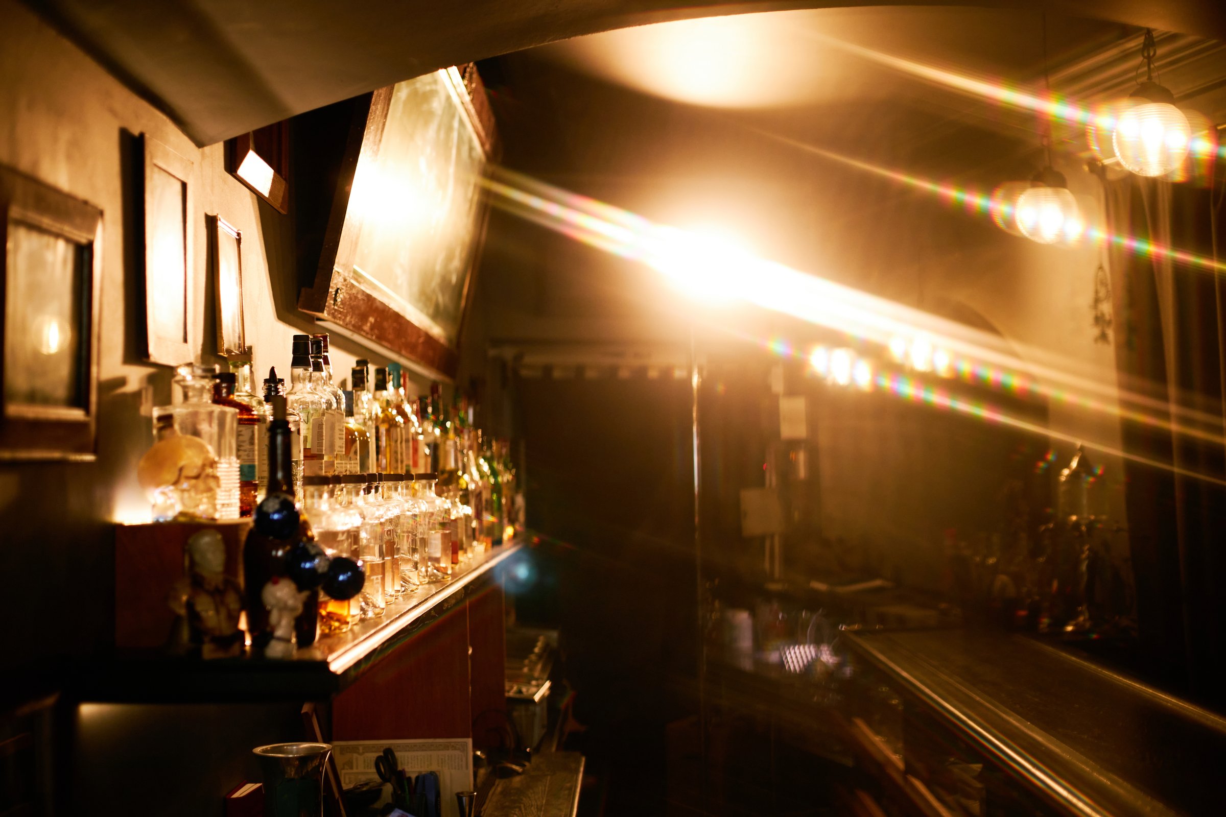 Interior of backlit bar with abundance of alcoholic beverages in jazz club, lens flare effect