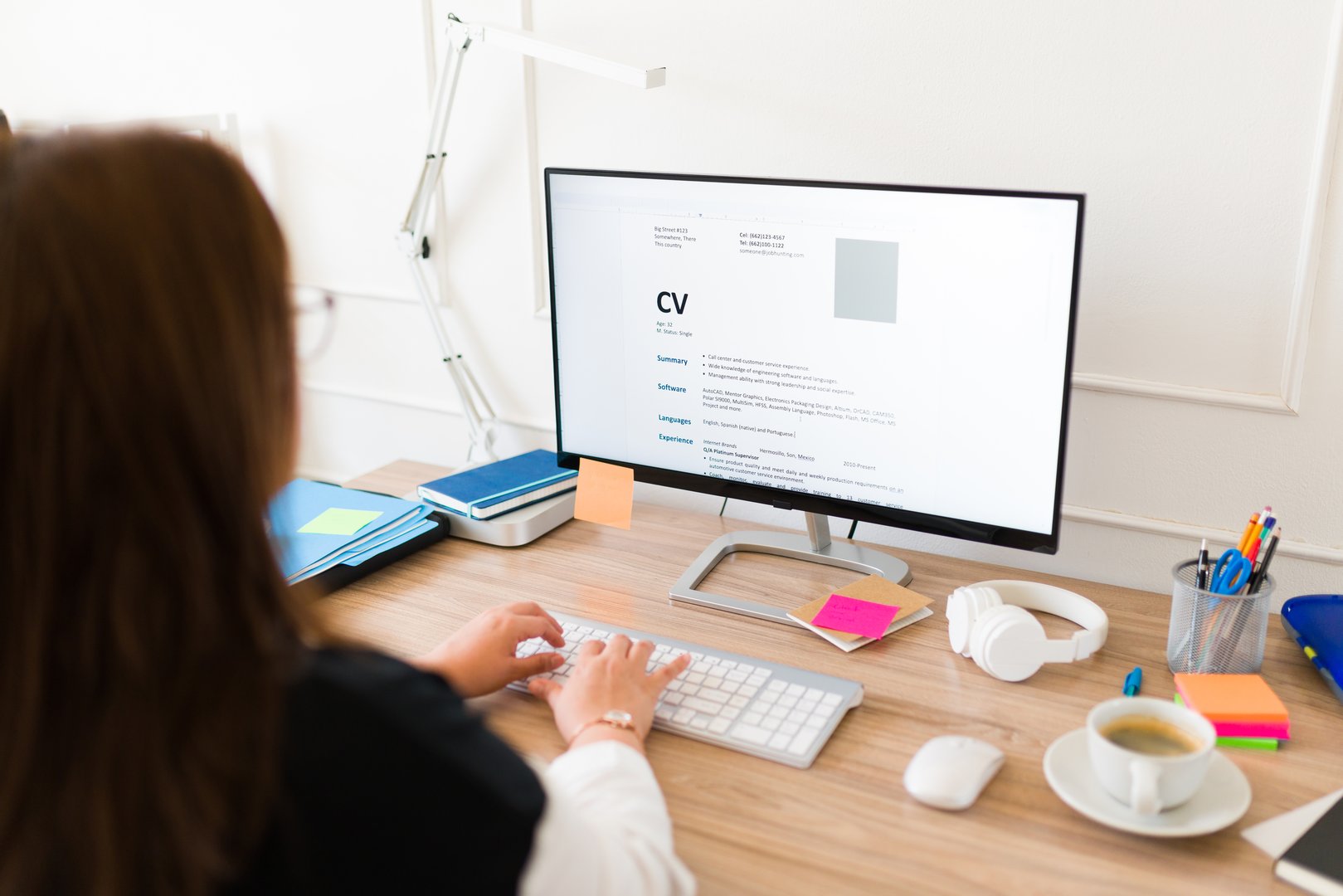 Professional woman seen from behind updating her curriculum or resume on the computer while applying for a new job