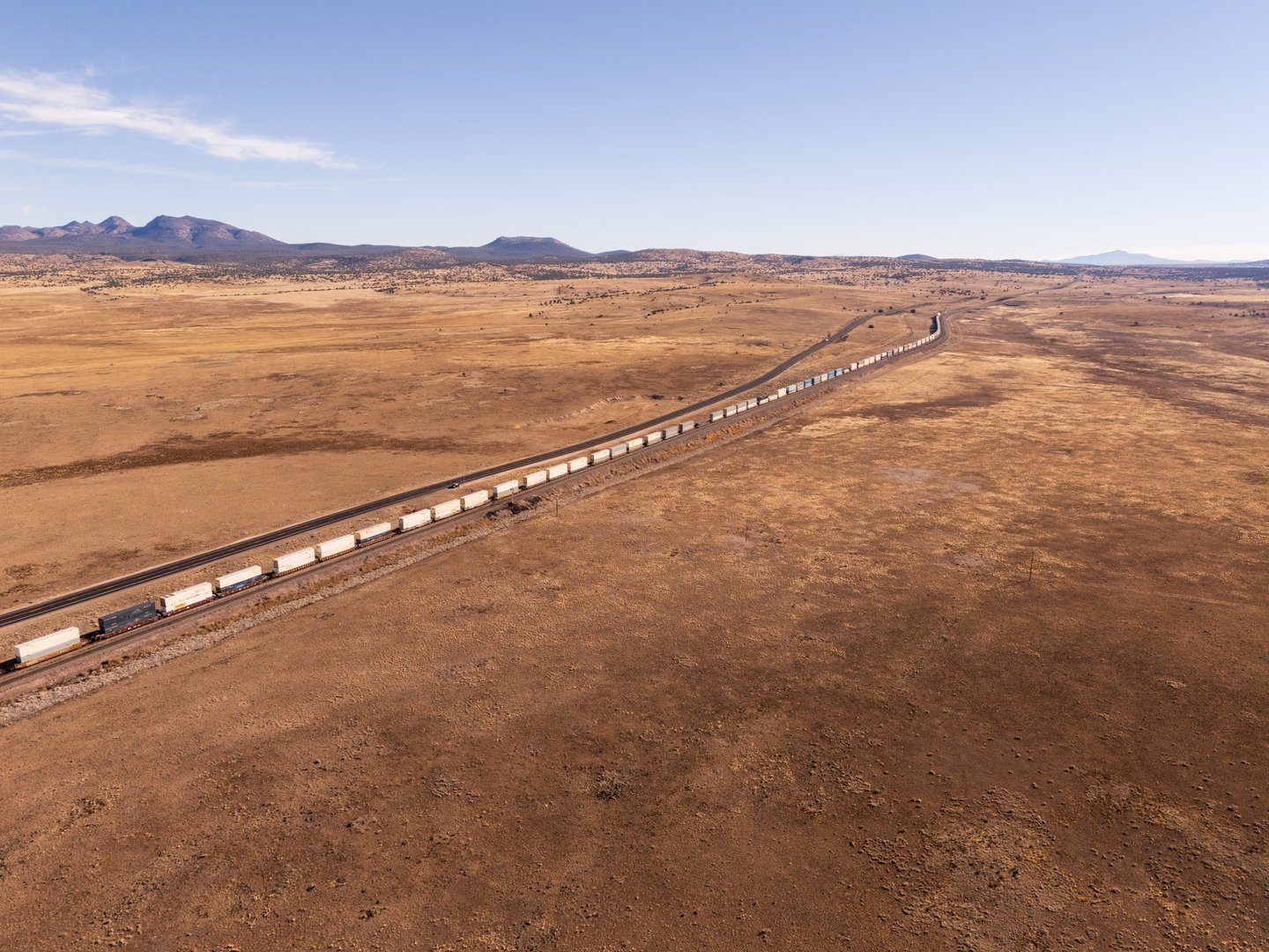 Freight train with containers on railway tracks through landscape