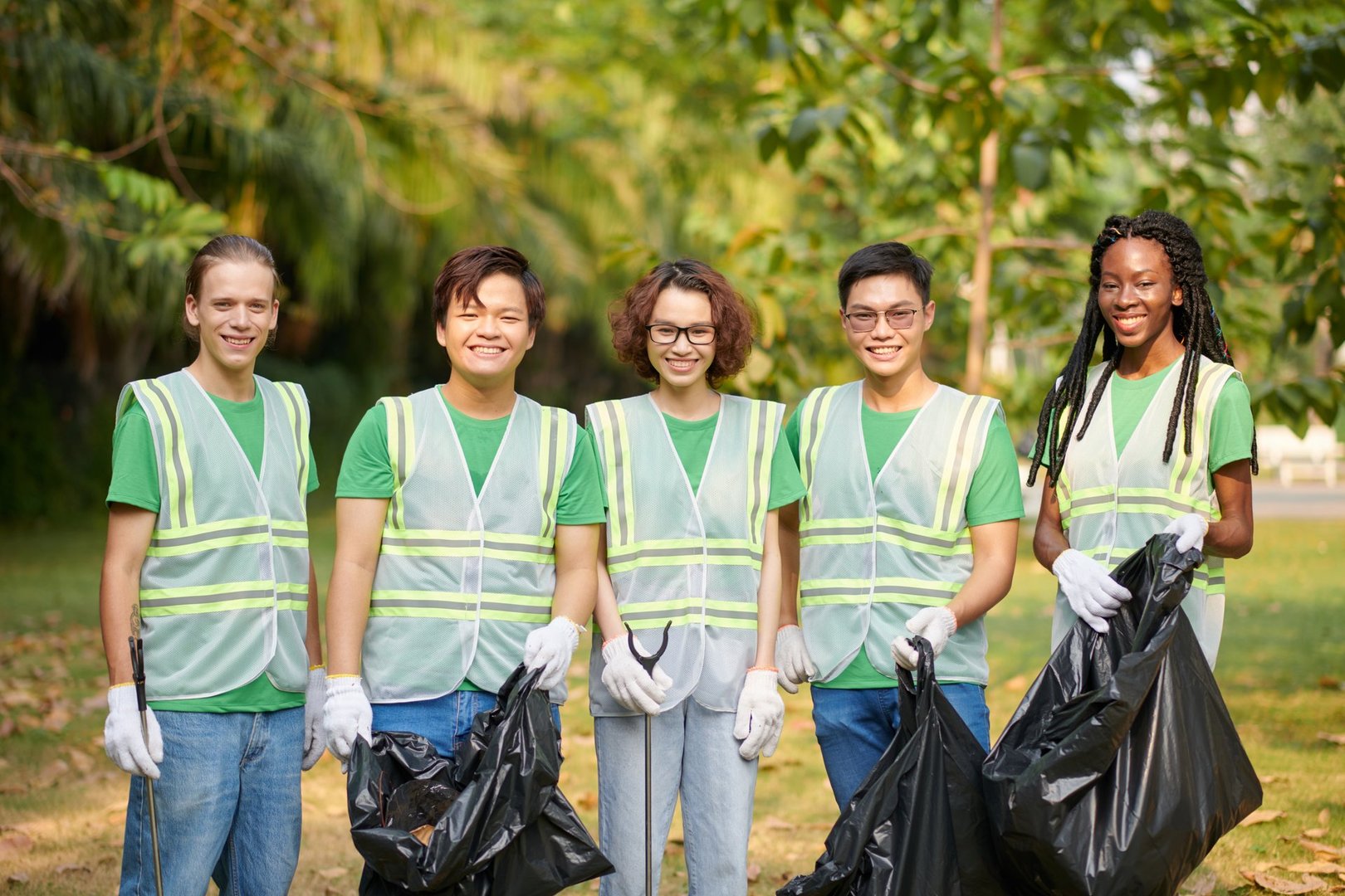 Diverse group of volunteers standing with bags of garbage they collected together
